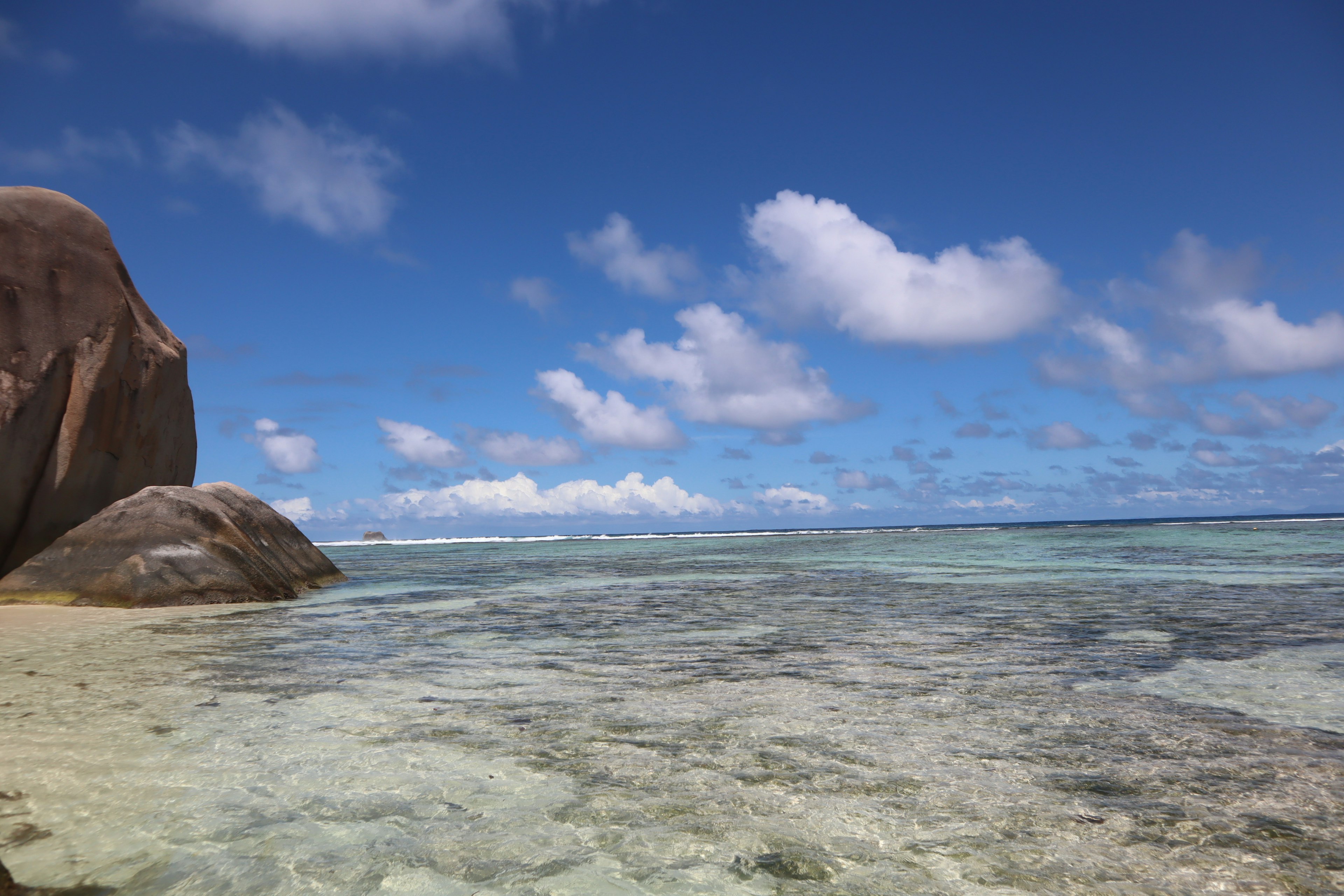 Pemandangan pantai dengan langit biru dan air jernih batu besar di tepi