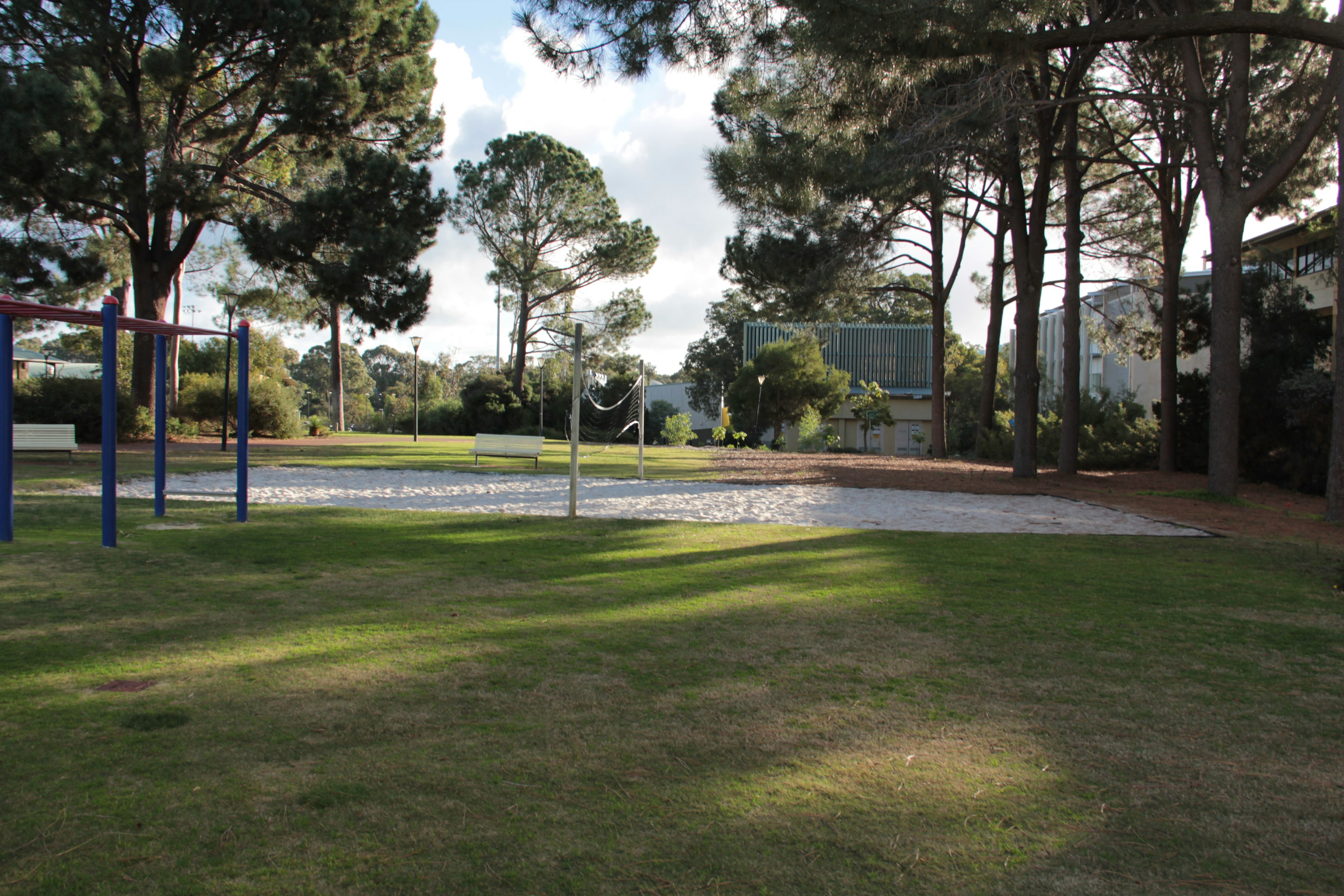 Área de juegos con césped verde y árboles en un parque