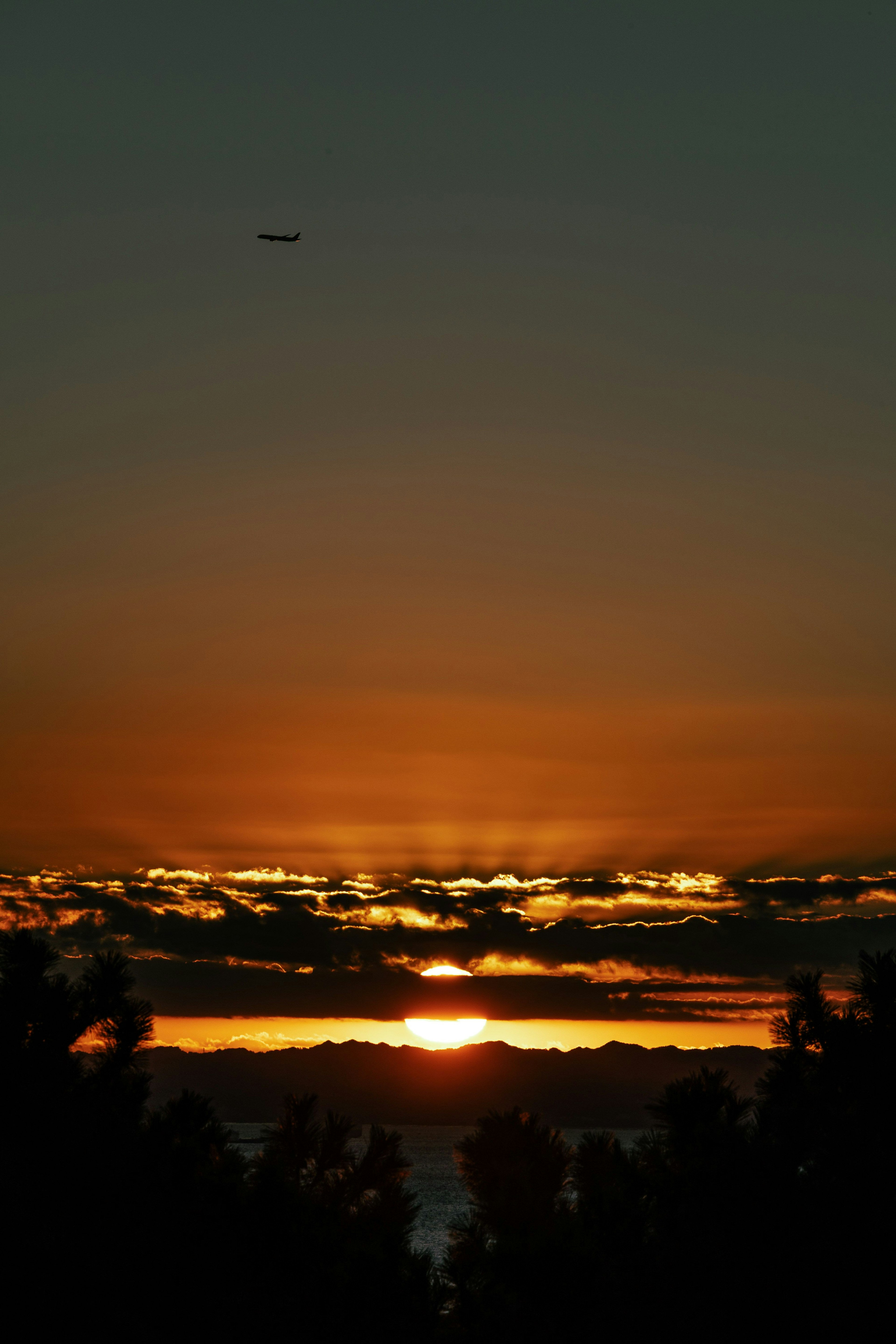 夕日が雲の間から見える美しい風景 飛行機が空を飛んでいる