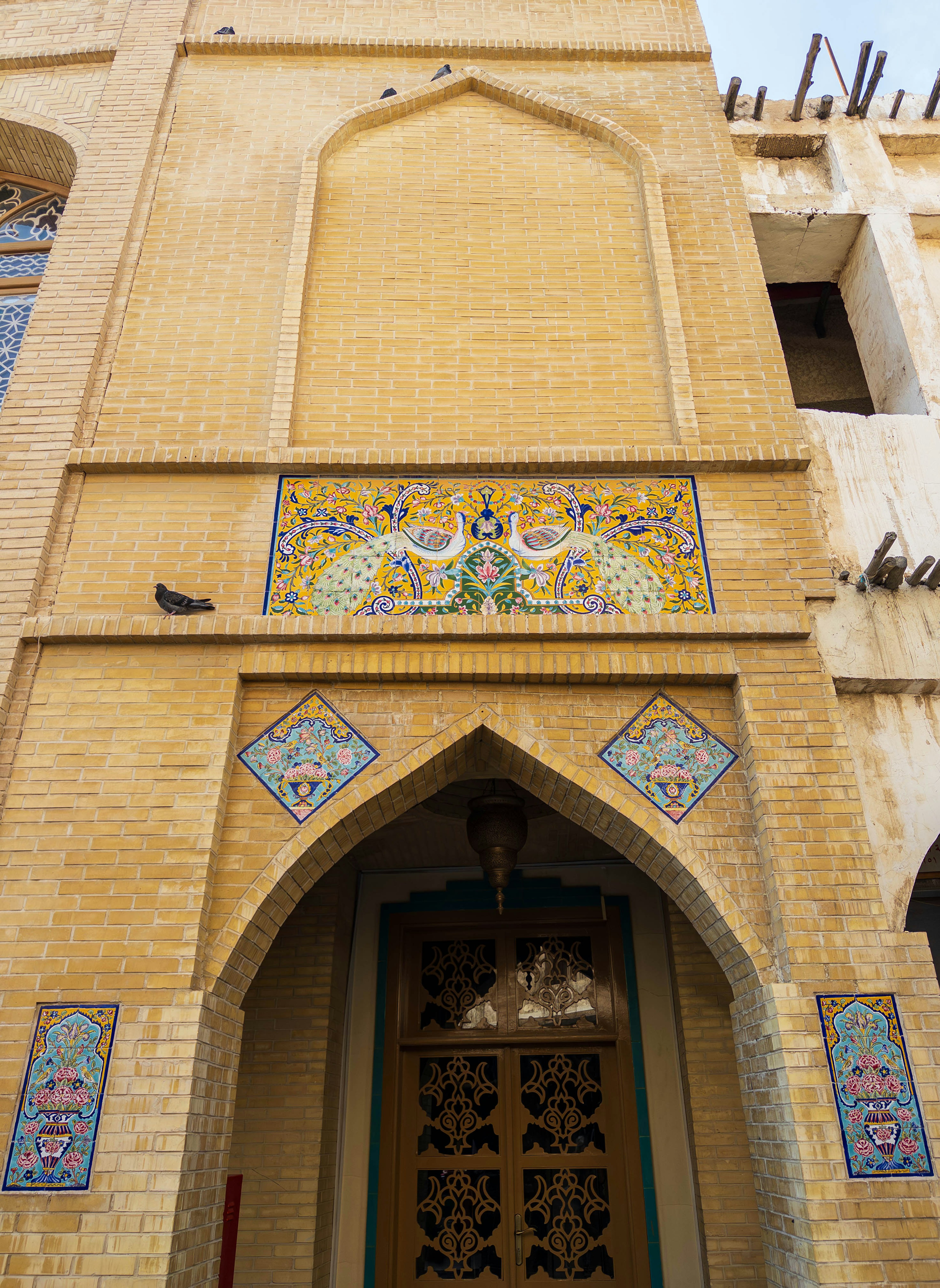 Entrée d'un bâtiment avec des décorations en mosaïque sur un mur jaune