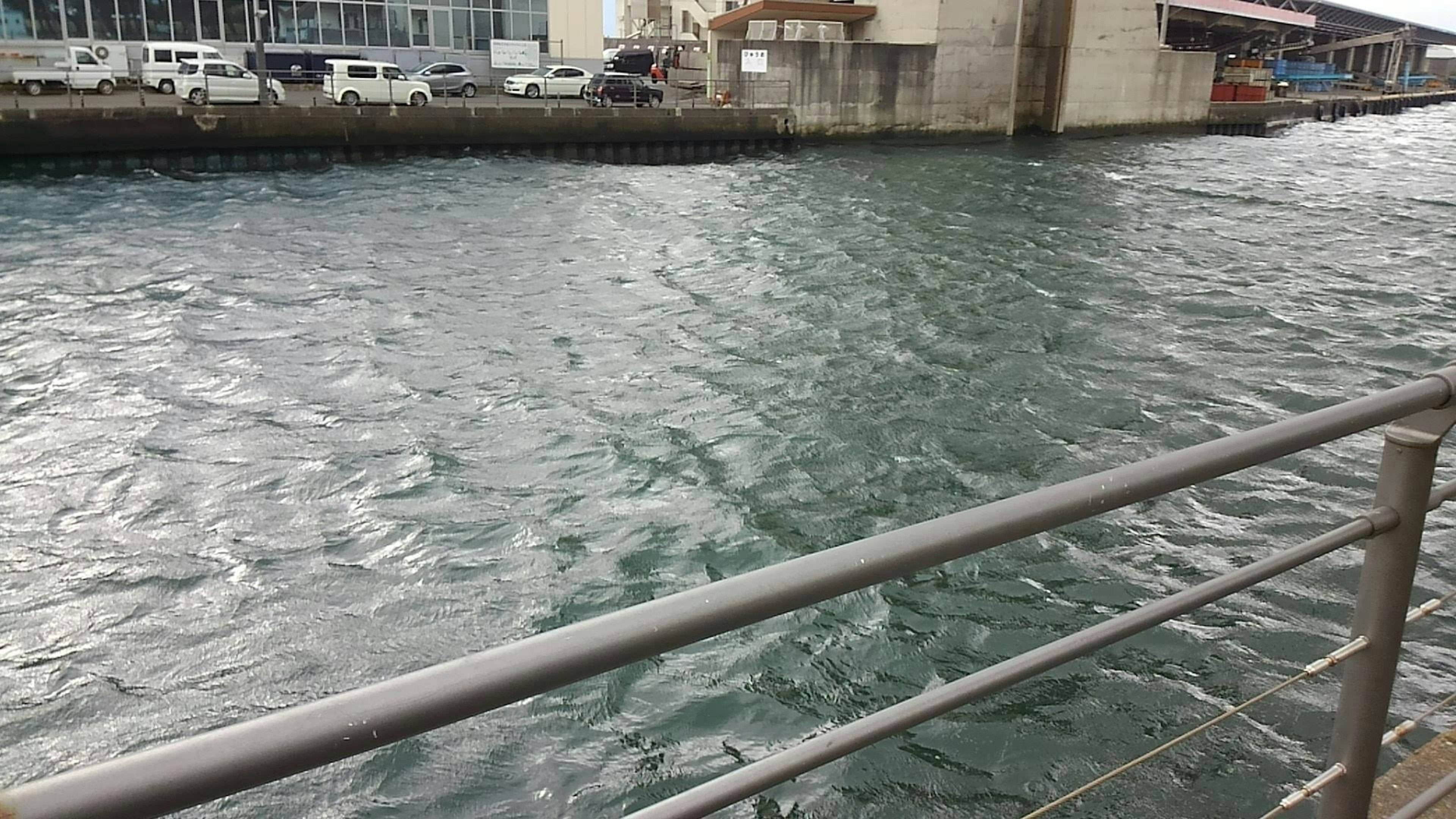 Vue de la surface de l'eau avec des ondulations et une rambarde dans un port