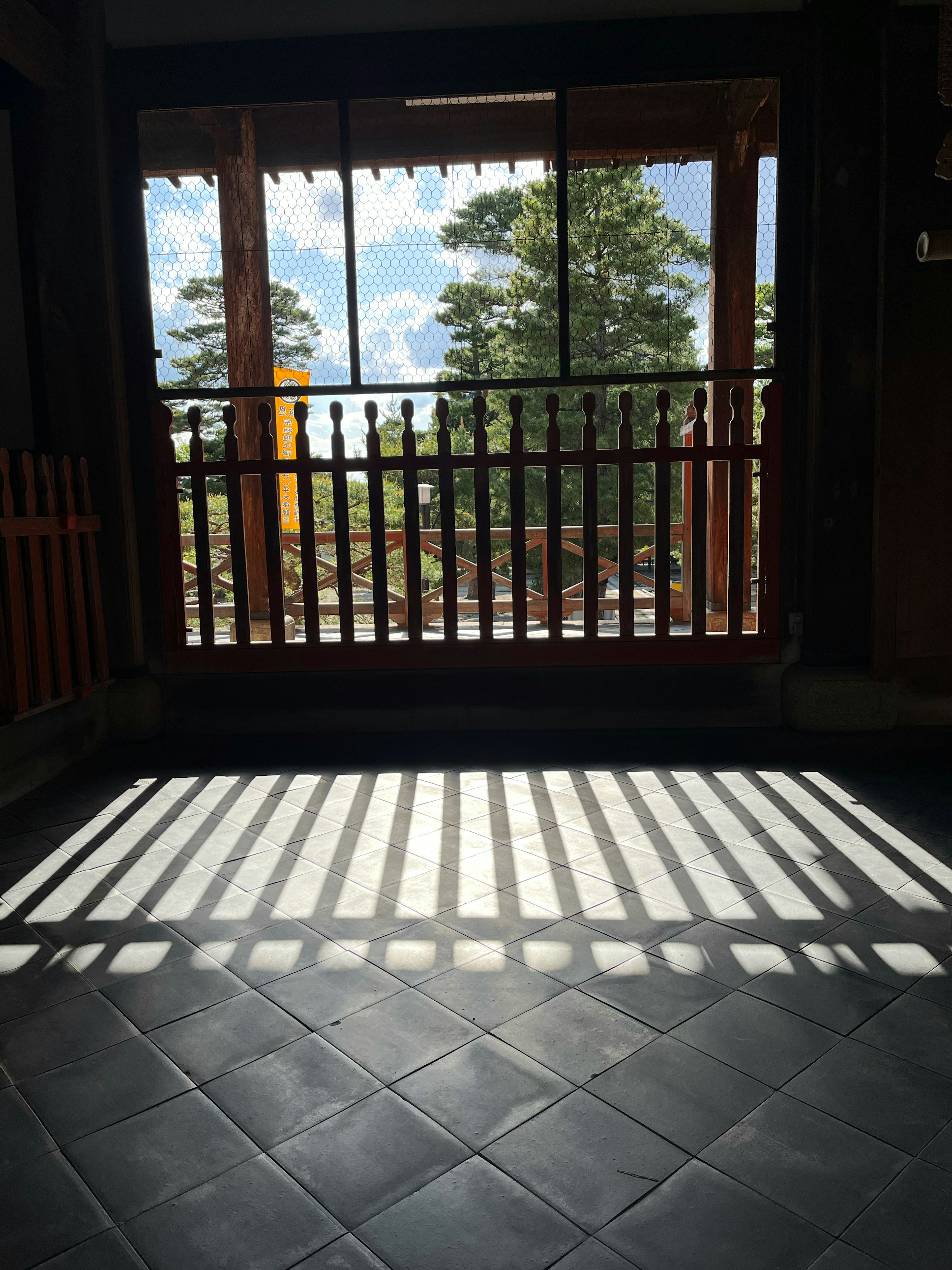 Innenraum mit Licht, das Schatten auf den Boden wirft von einem Fenster mit Blick auf Bäume