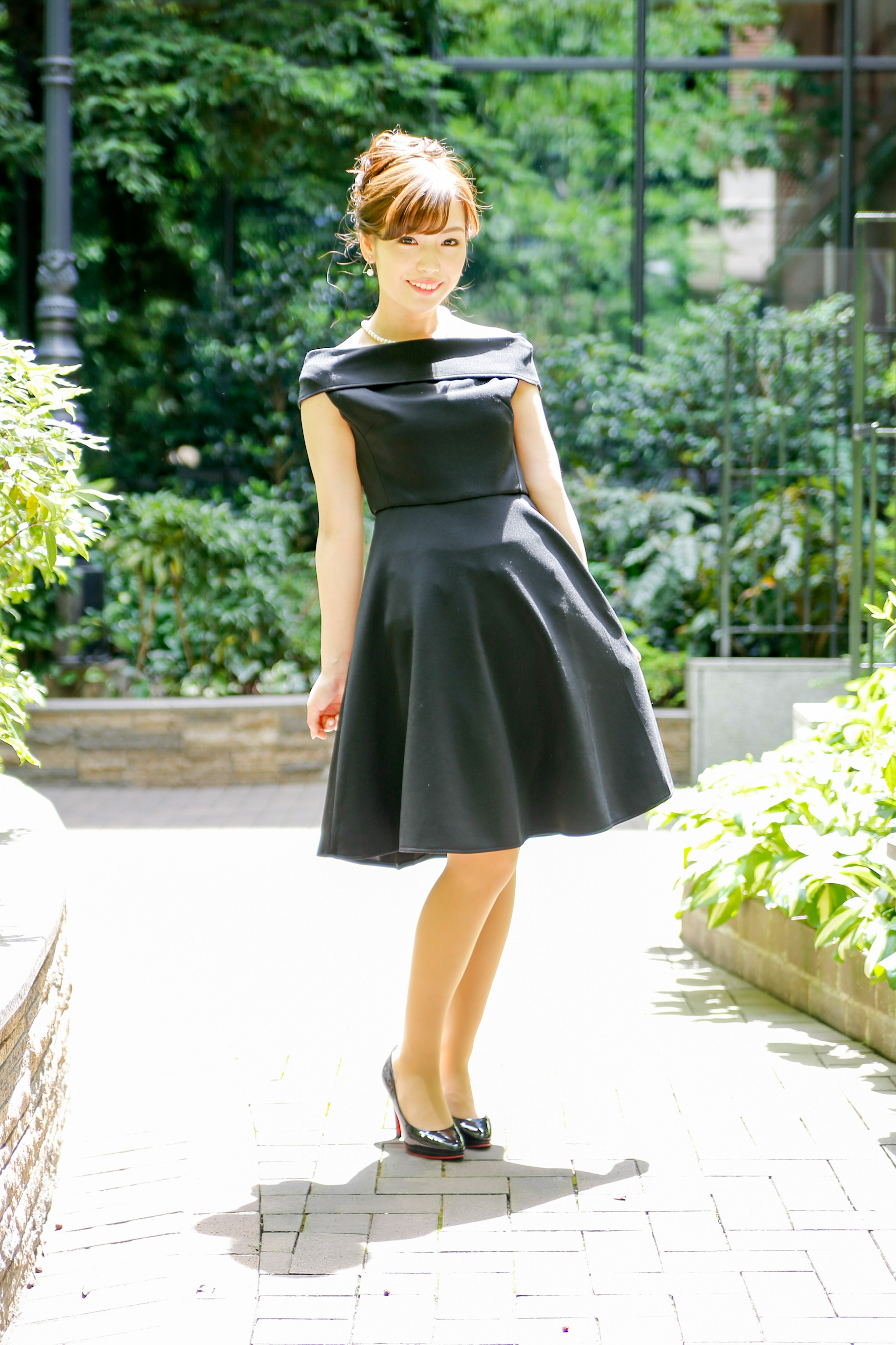 A woman wearing a black dress posing in a garden