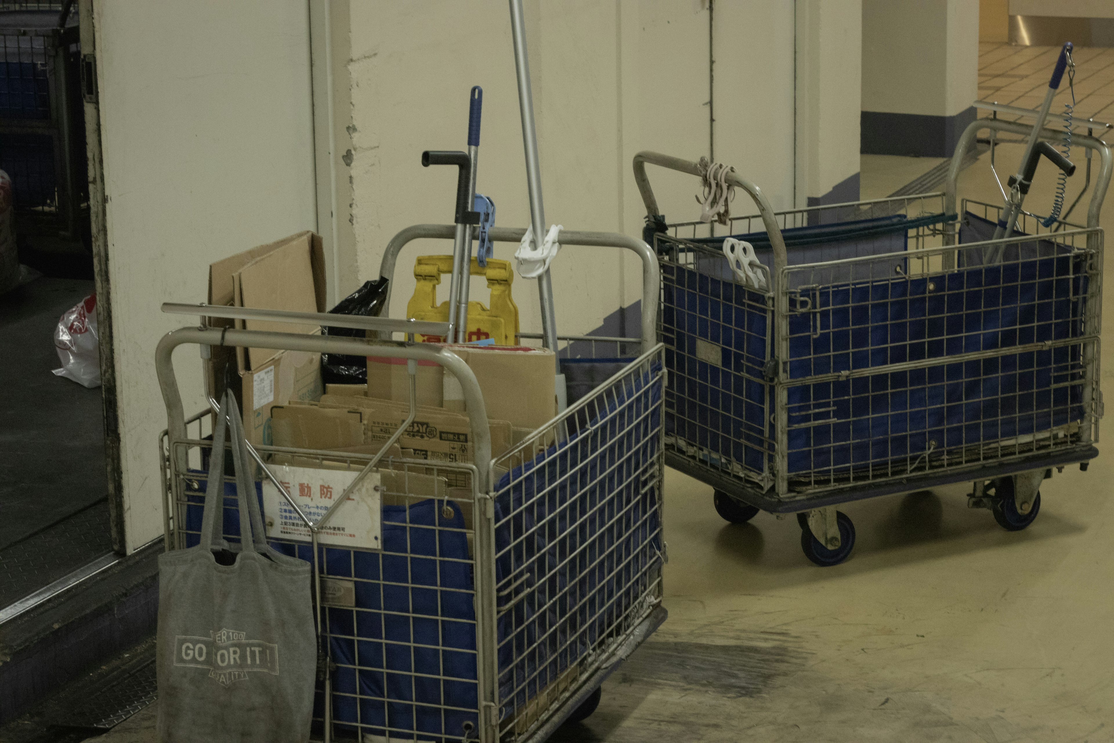 Indoor scene with two transport carts loaded with cardboard boxes and cleaning equipment