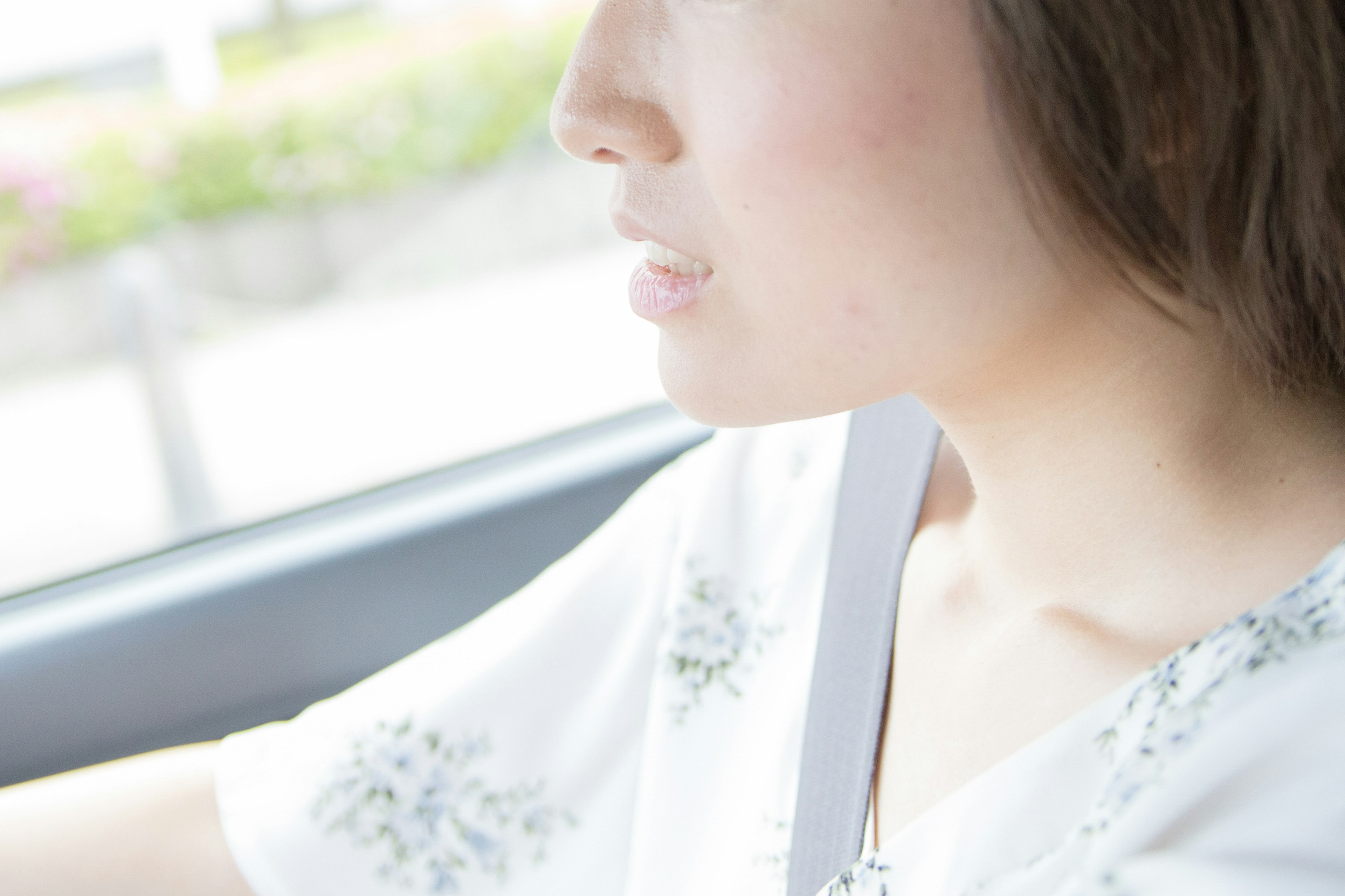 Profile of a woman driving wearing a white blouse with a seatbelt blurred background