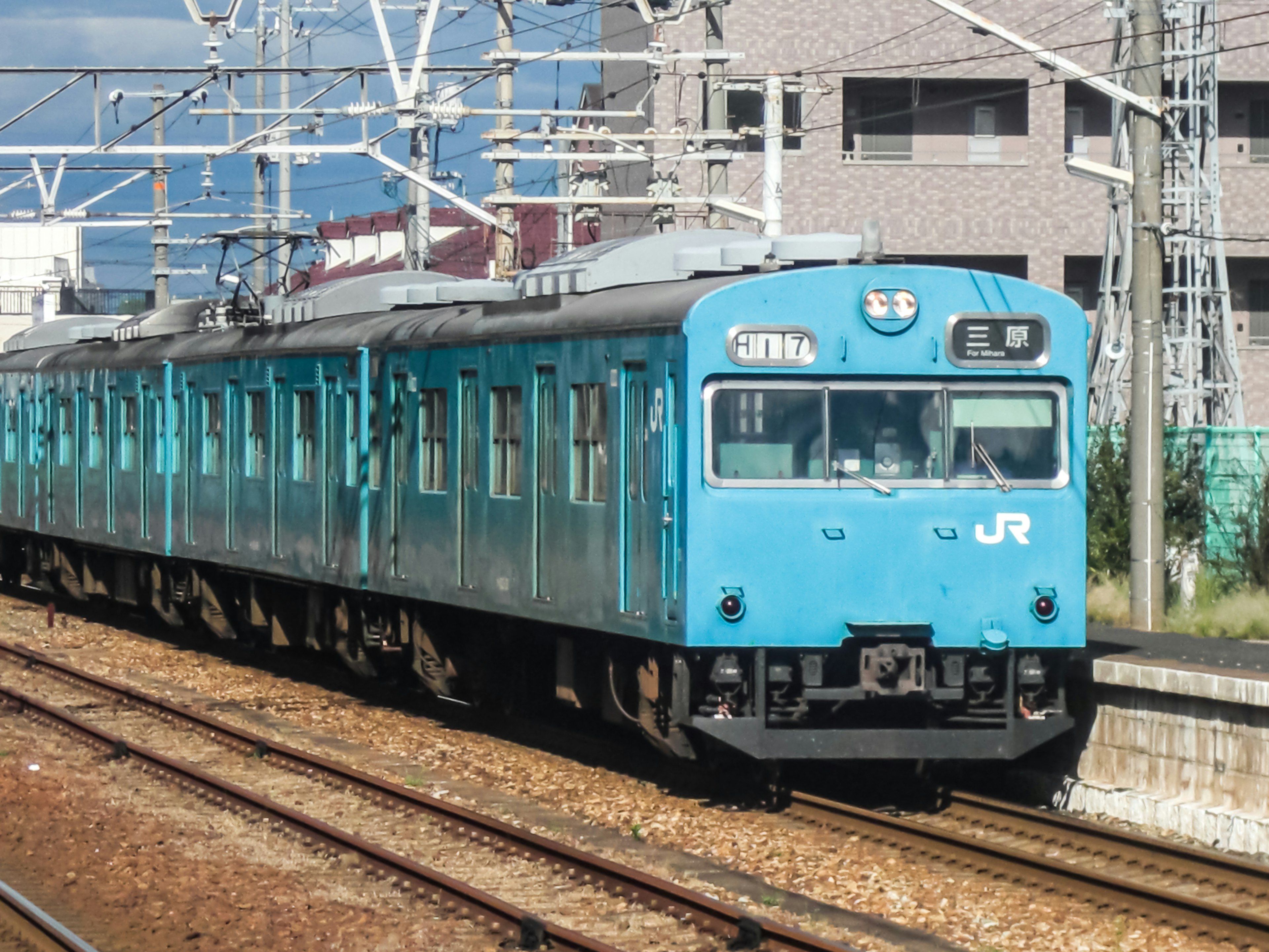 青いJR電車が線路を走る風景