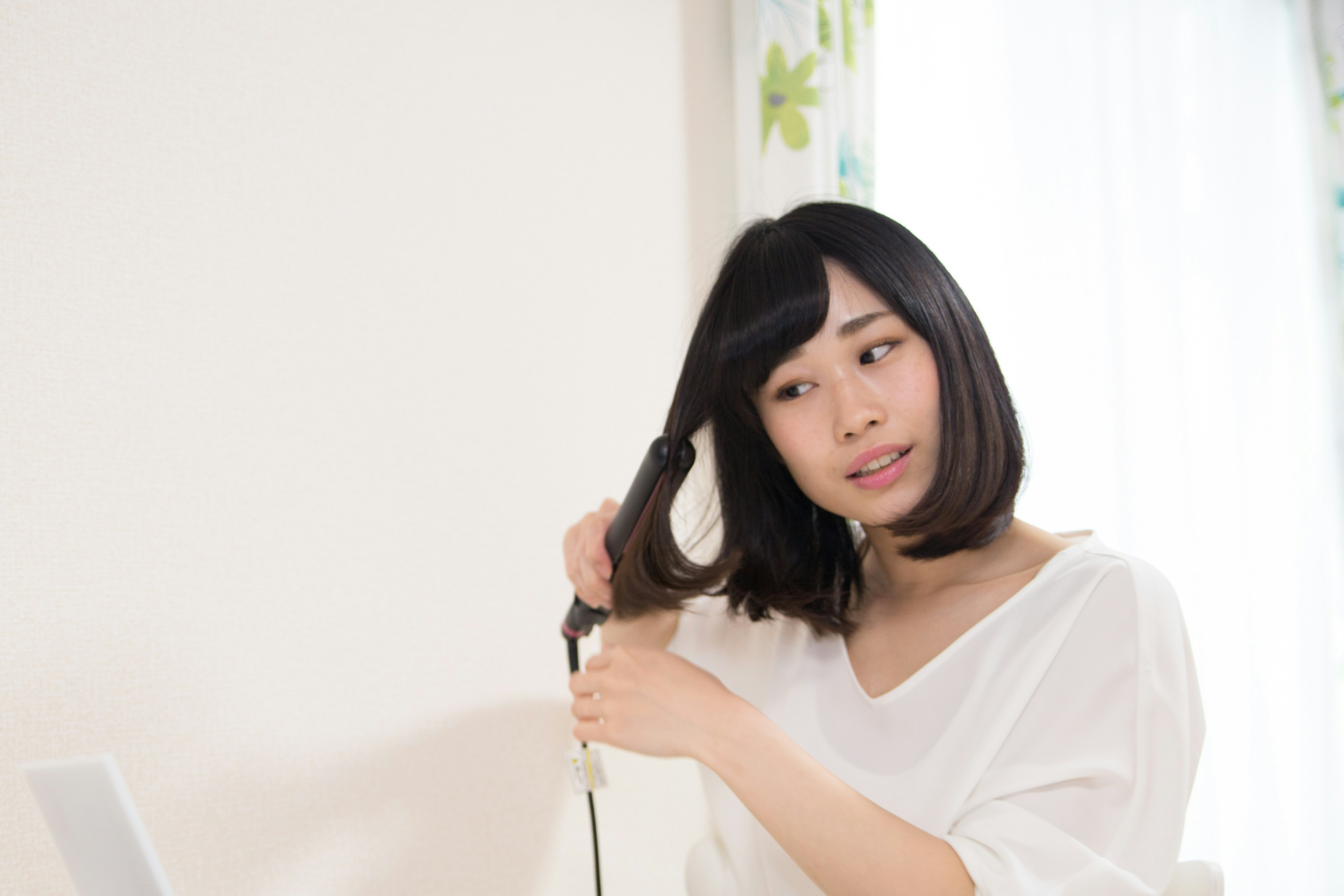 A woman styling her hair with a curling iron