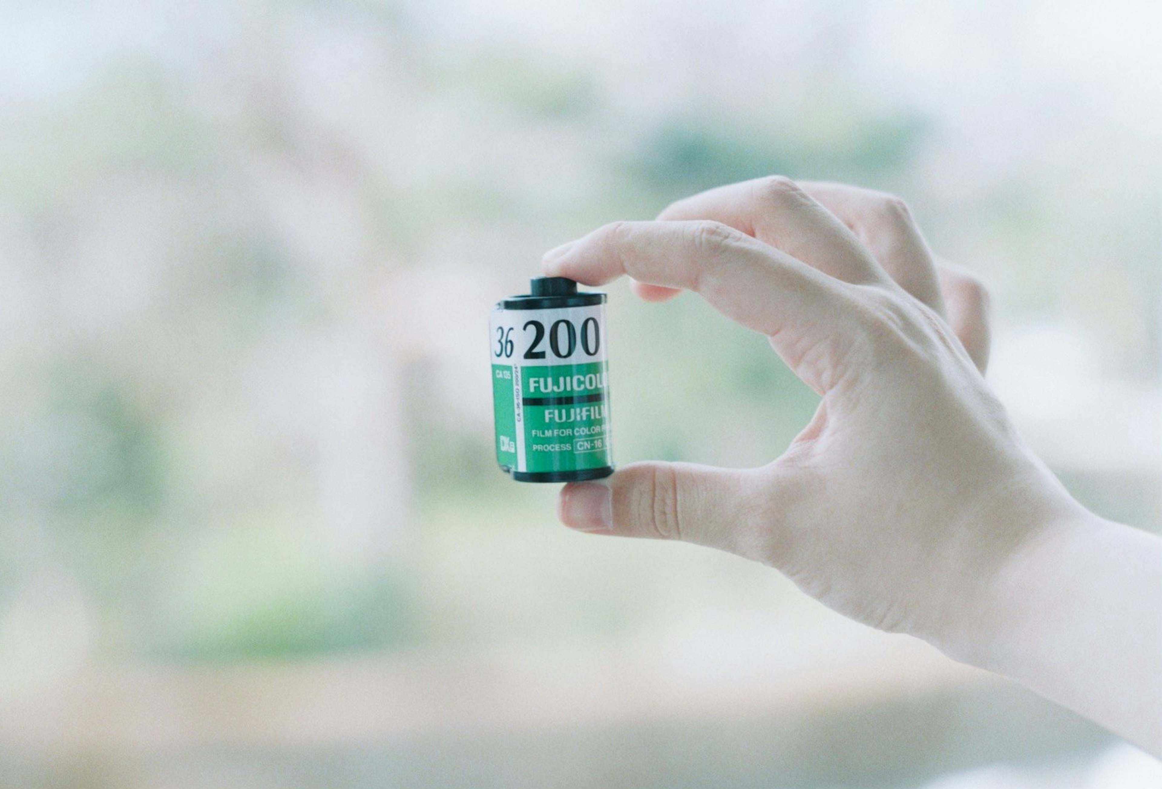 A hand holding a roll of 200 film for cameras