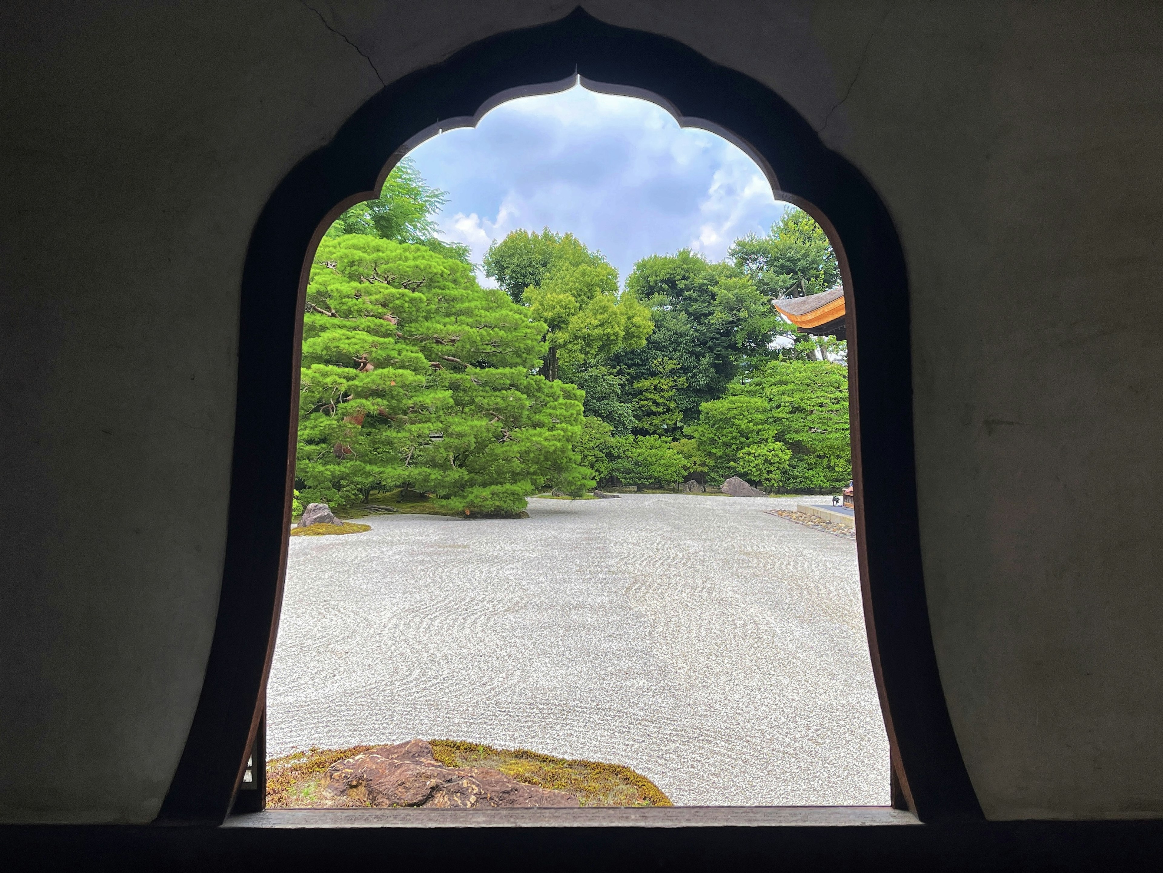 Ventana en arco enmarcando un jardín sereno con vegetación exuberante