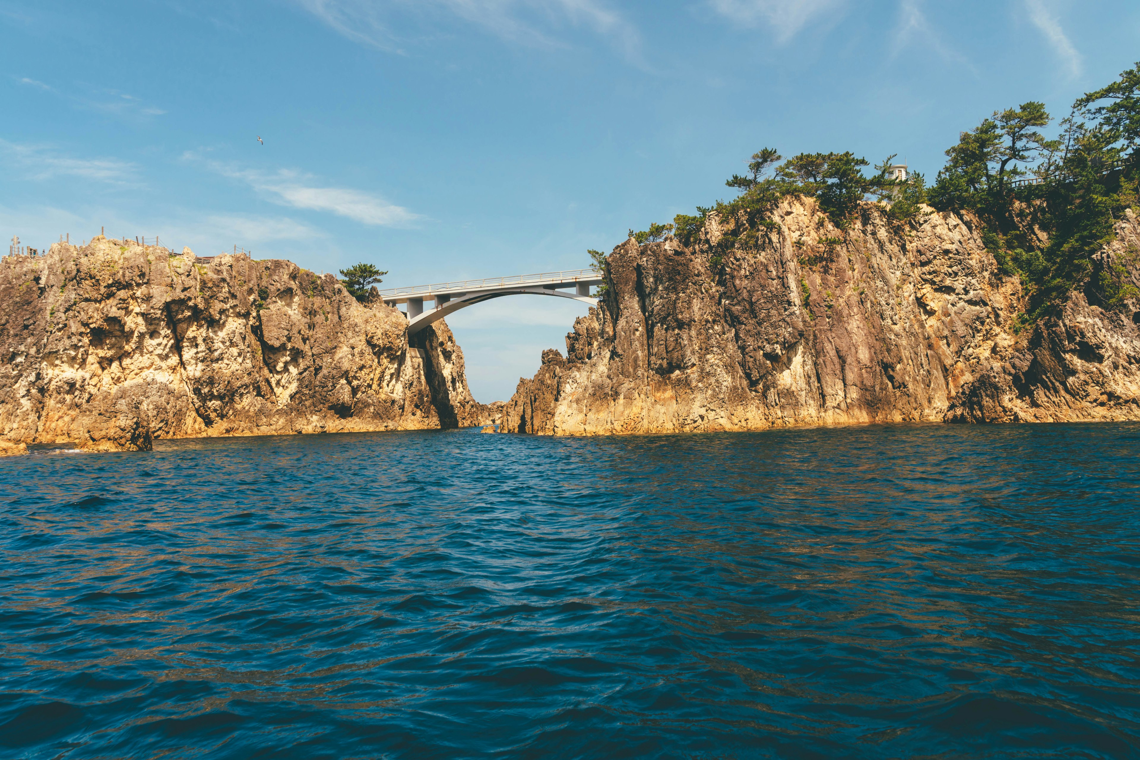 Scenic view of a rocky coastline with a bridge over turquoise water