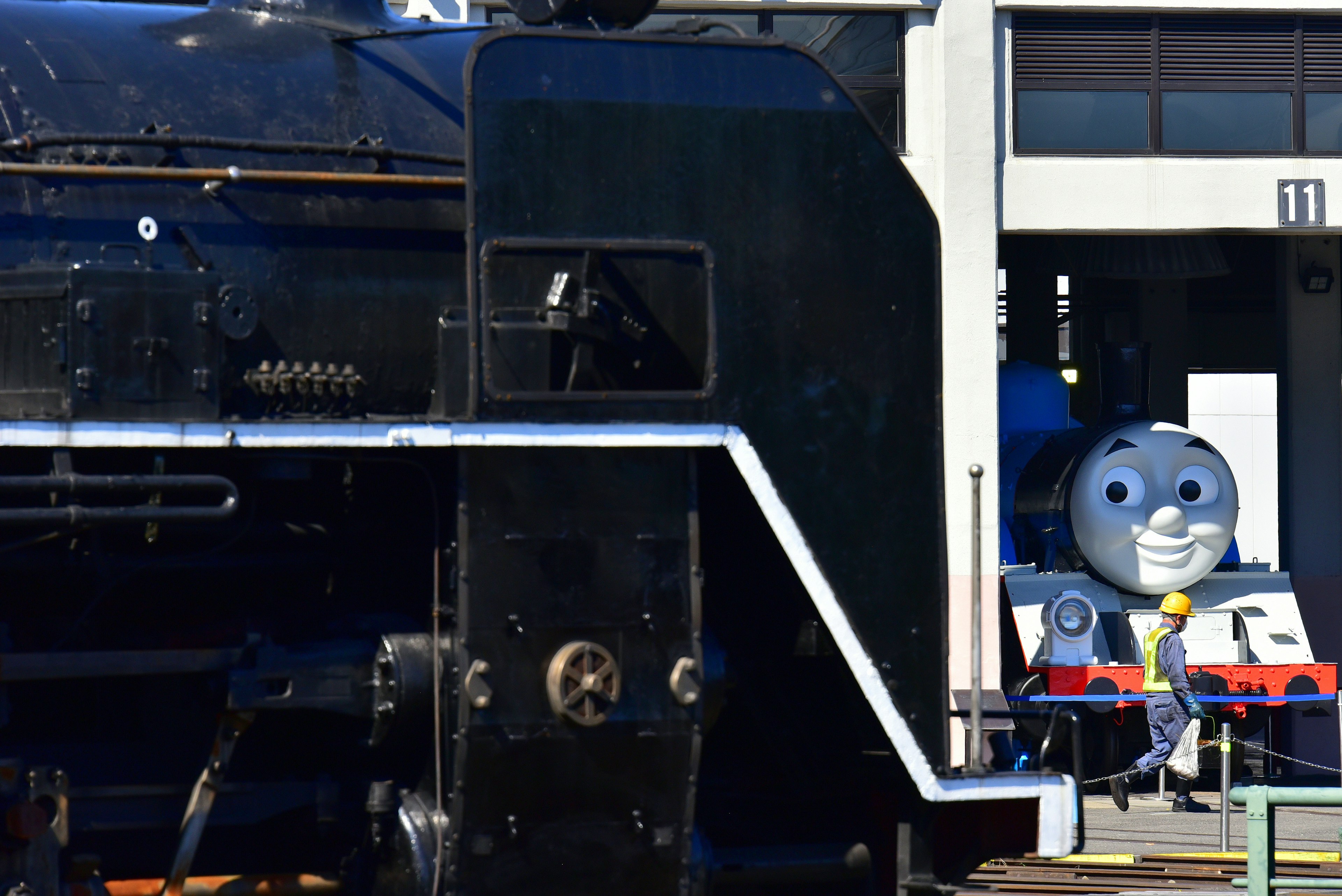 Une locomotive à vapeur noire à côté d'un personnage bleu Thomas le Tank Engine