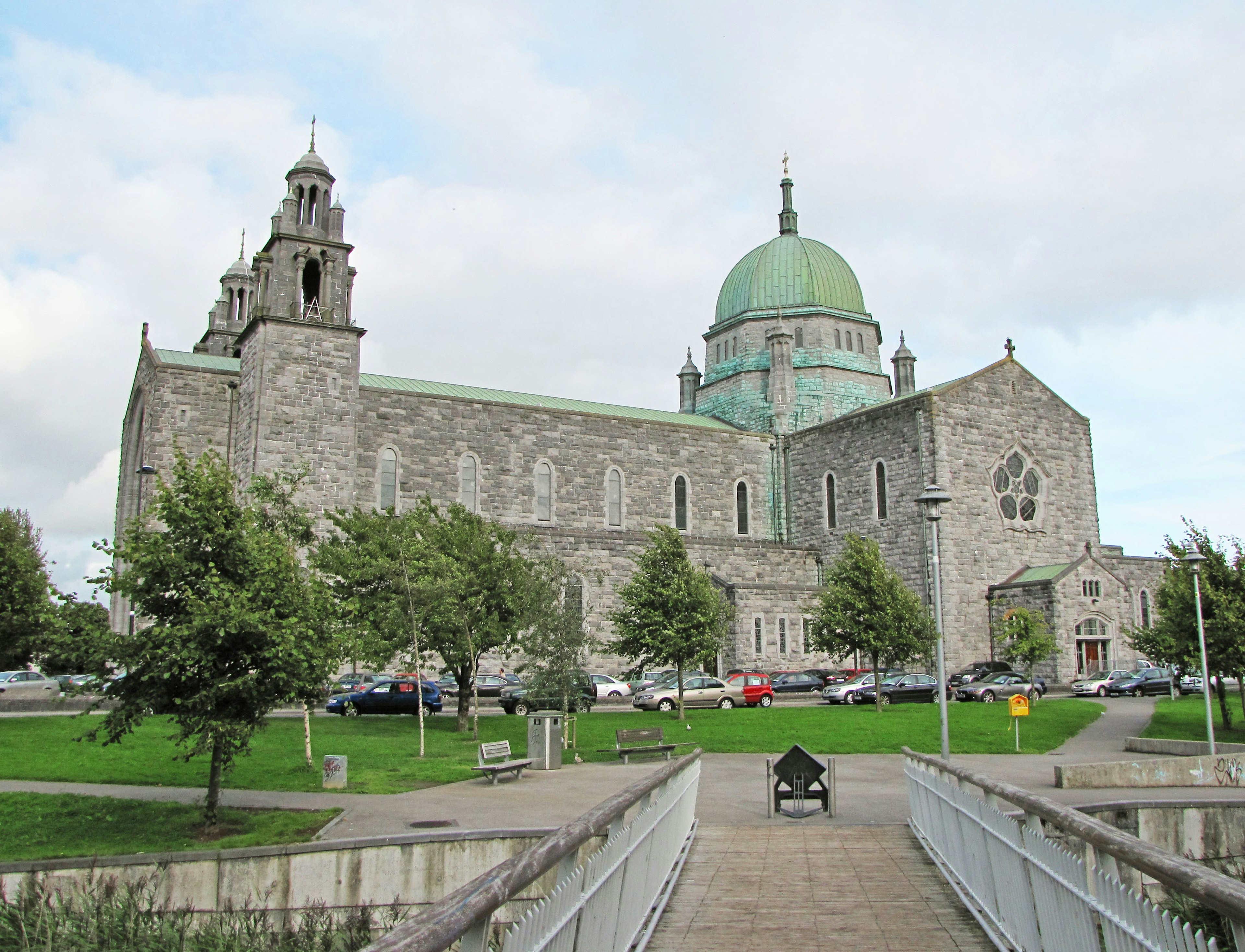 Stone cathedral with a green dome and surrounding greenery