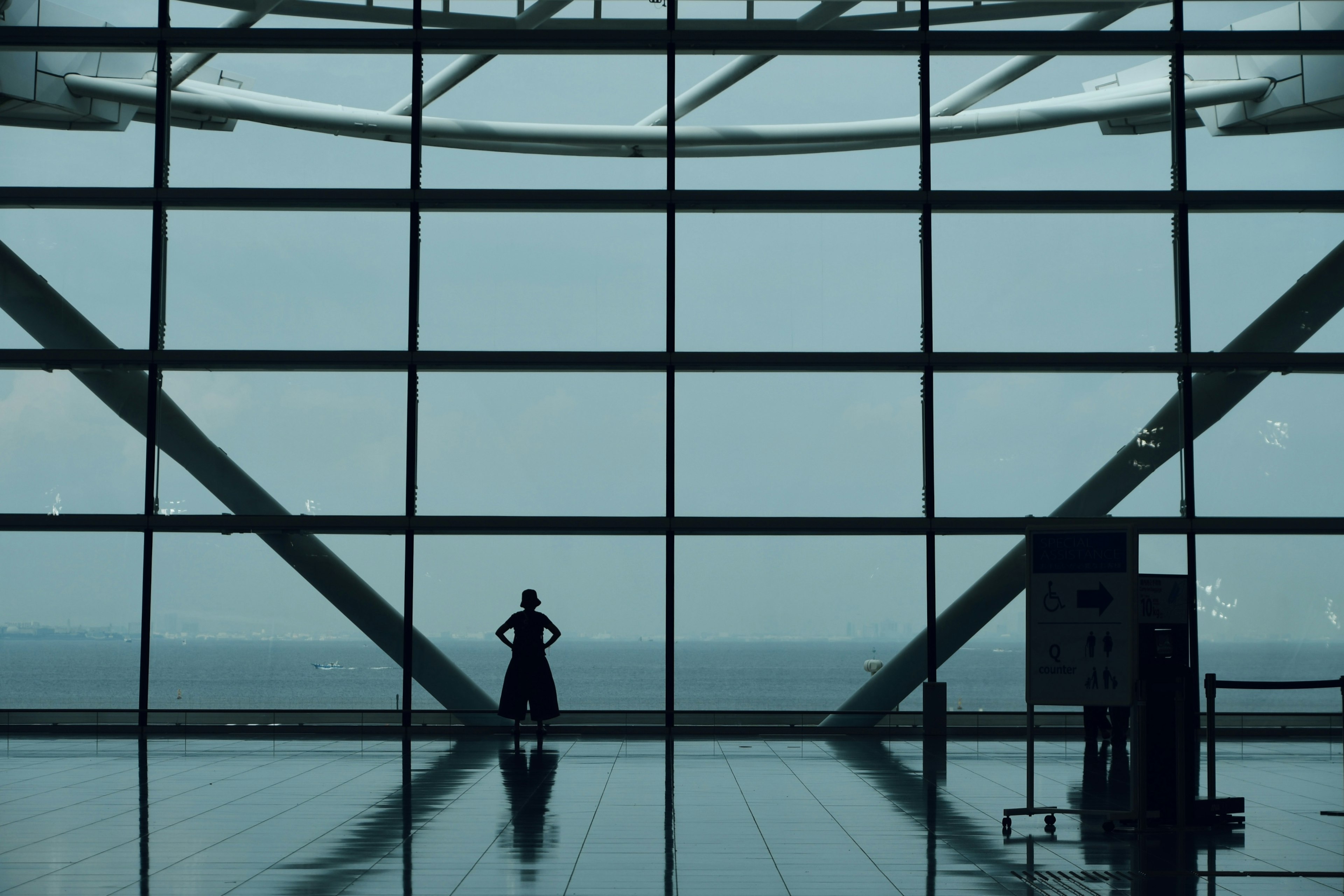 Silhouette einer Person, die an großen Glasfenstern in einem Flughafen steht