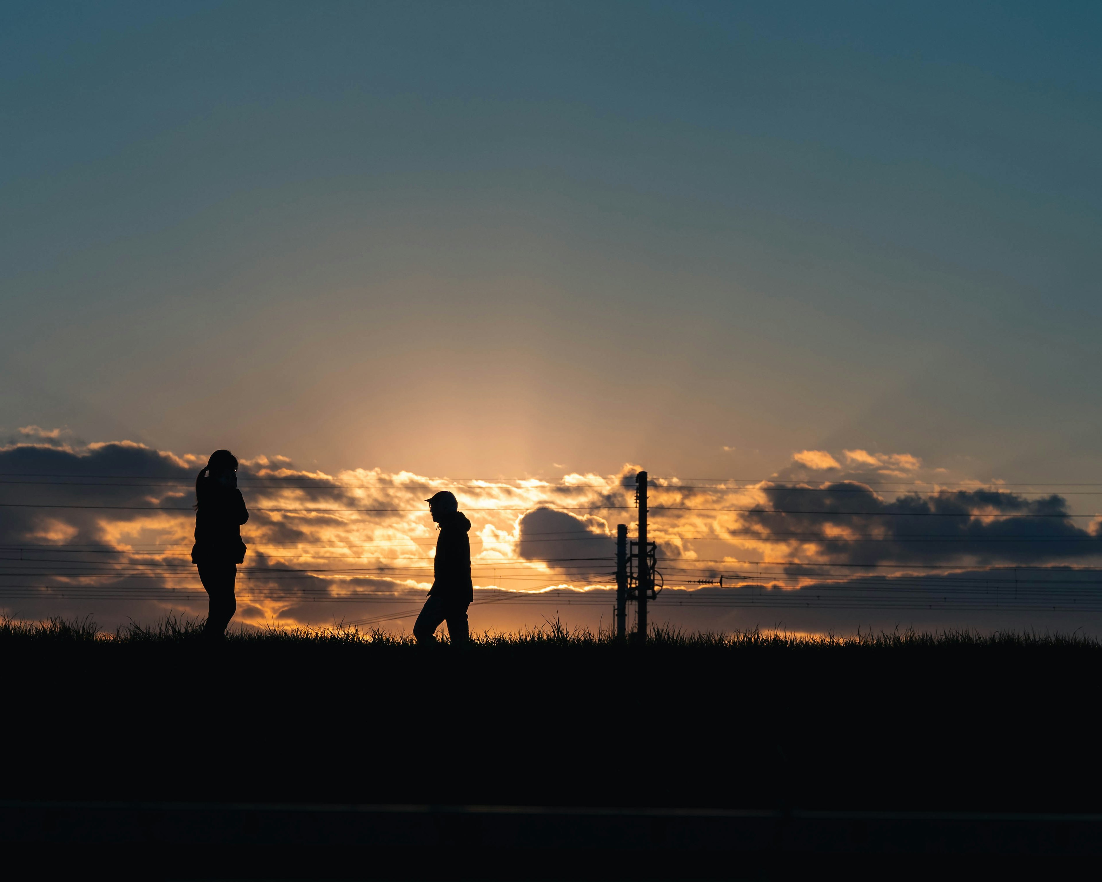 Silhouette di due persone contro uno sfondo di tramonto