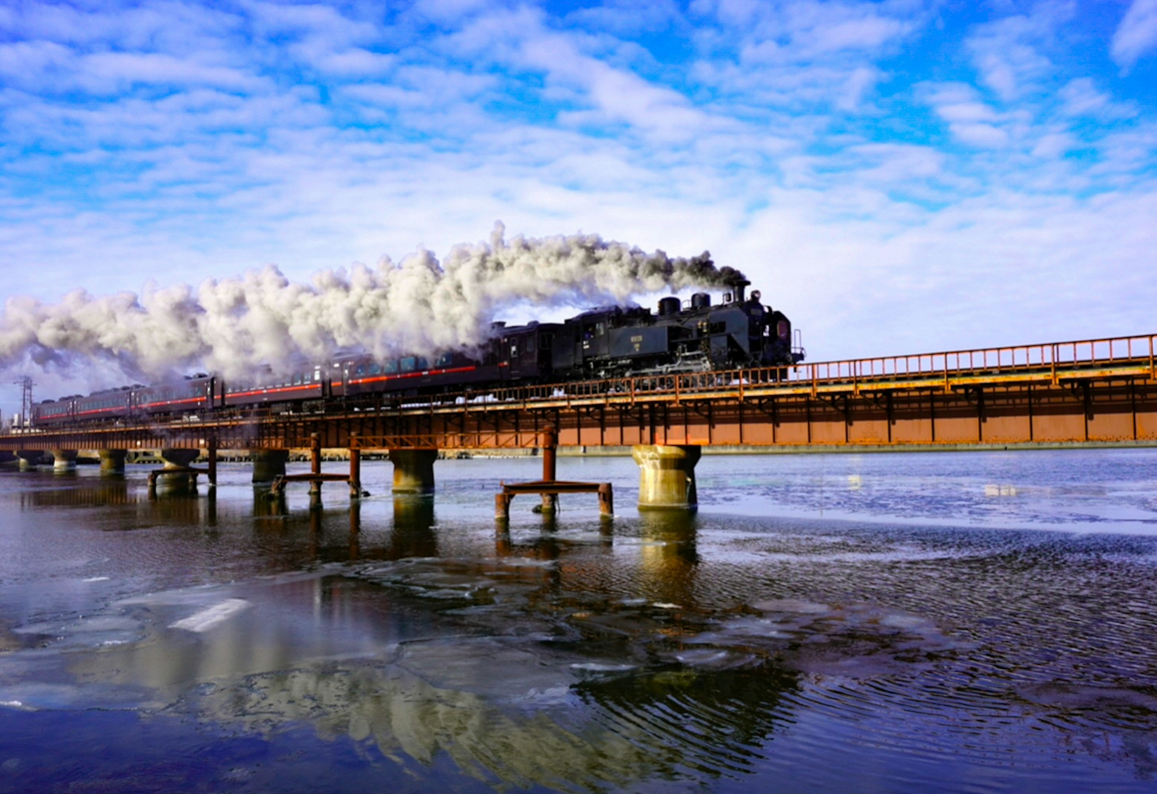 蒸気機関車が橋を渡る風景 青空と雲の背景