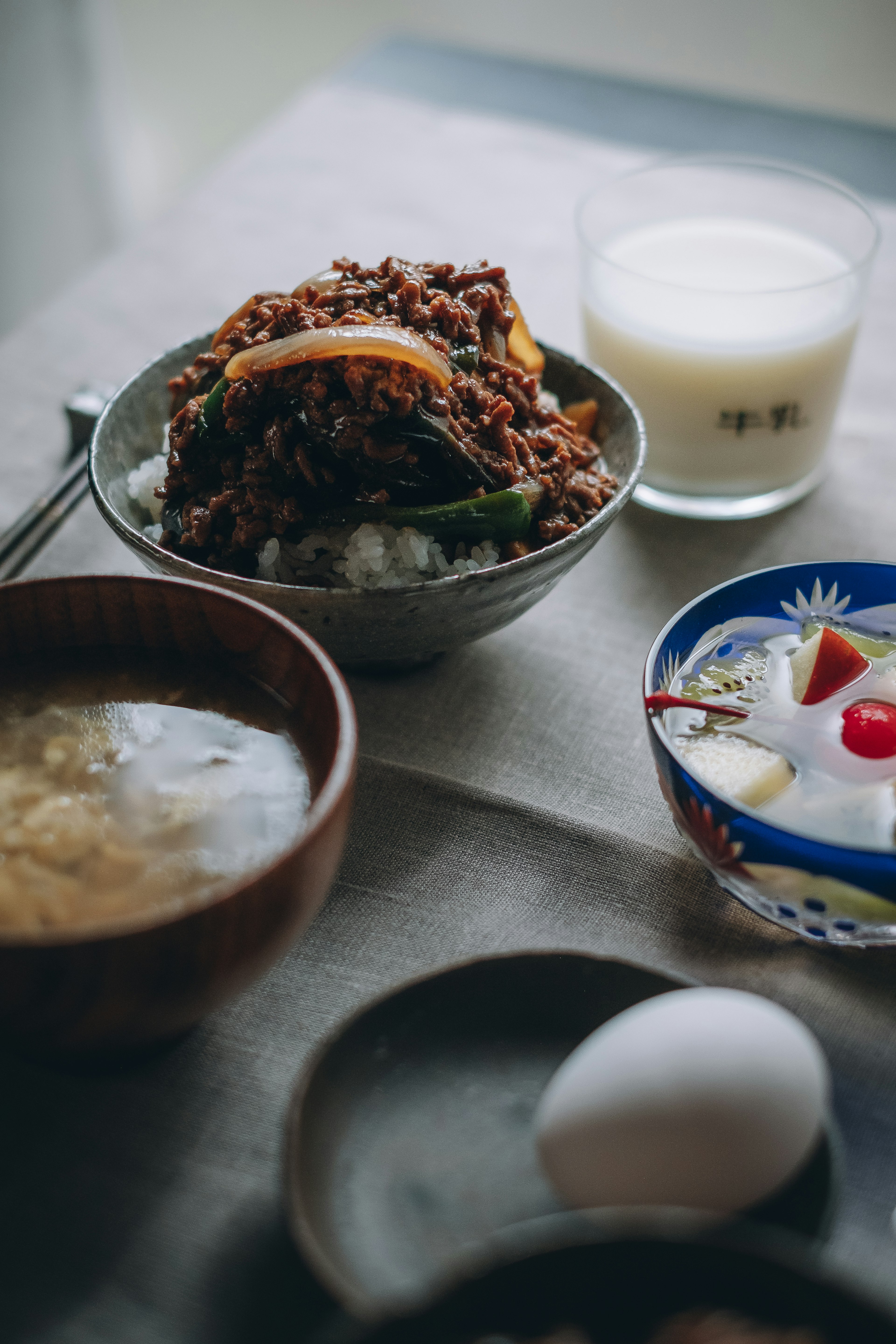 Japanisches Essen mit Reis, belegt mit Fleisch und Gemüse, dazu Milch und Dessert