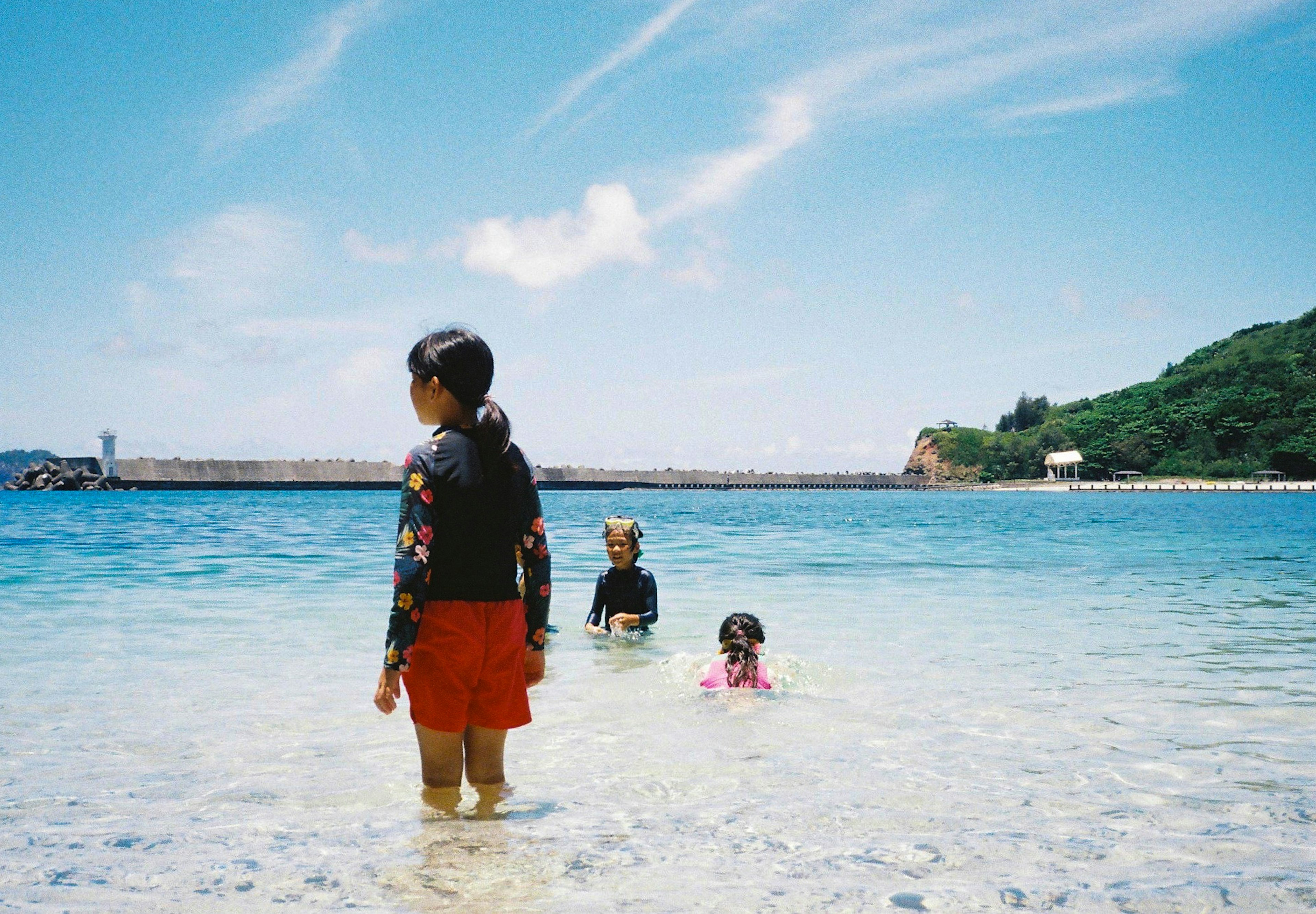 Niños jugando en el mar con un cielo azul claro y agua transparente