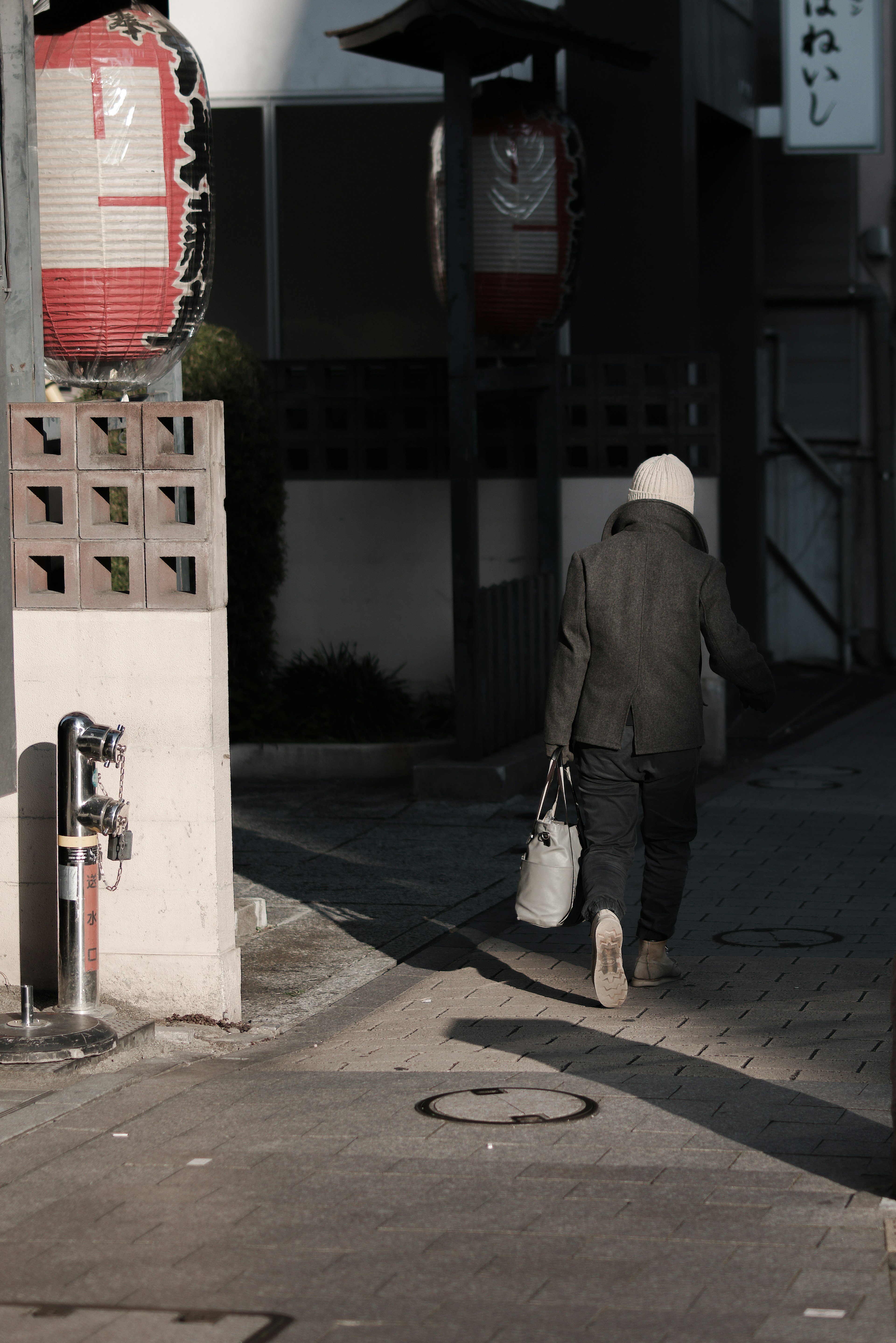 Una persona che cammina all'angolo di una strada con lanterne