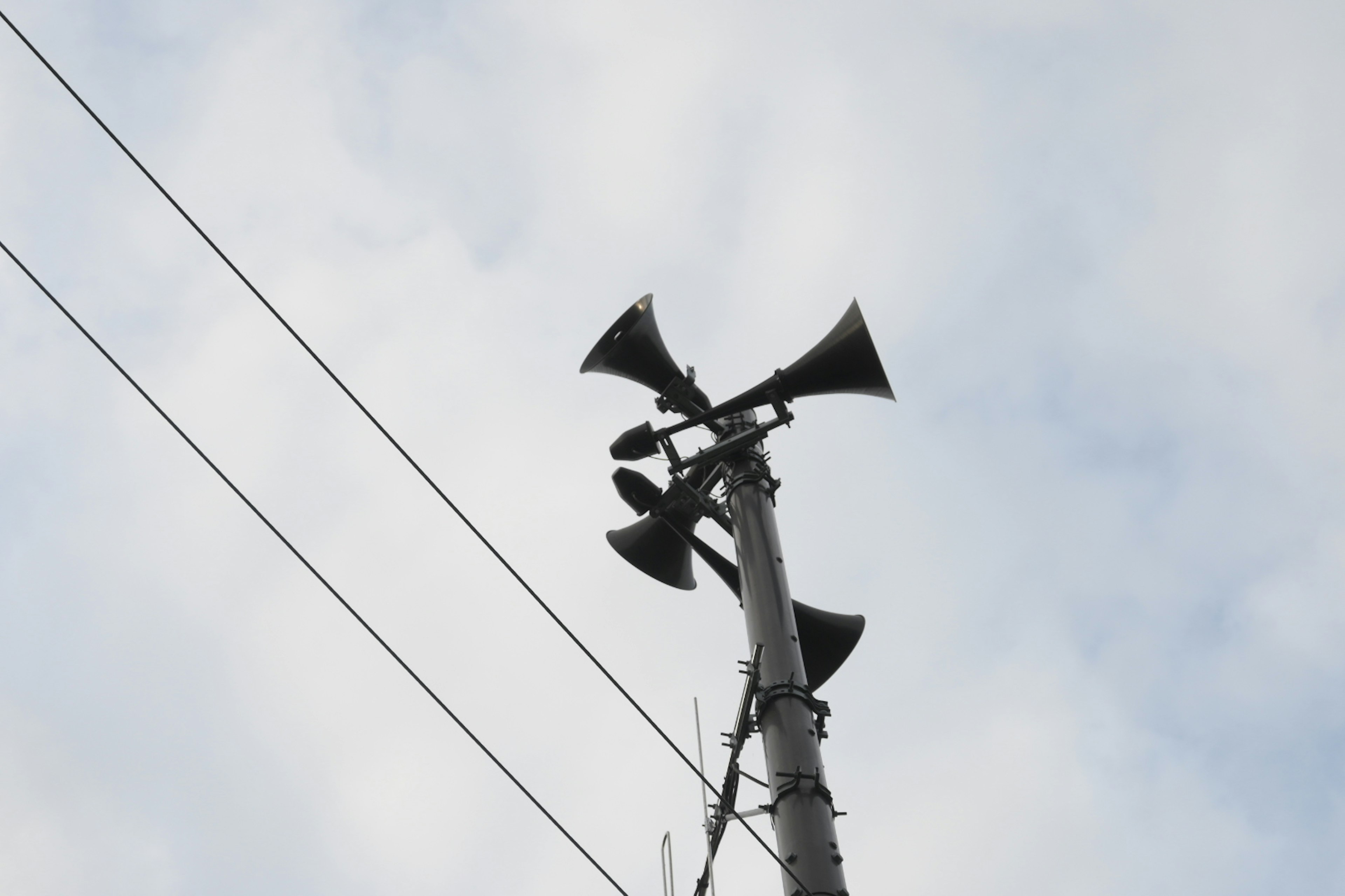 空に向かって立つスピーカーの塔と曇り空