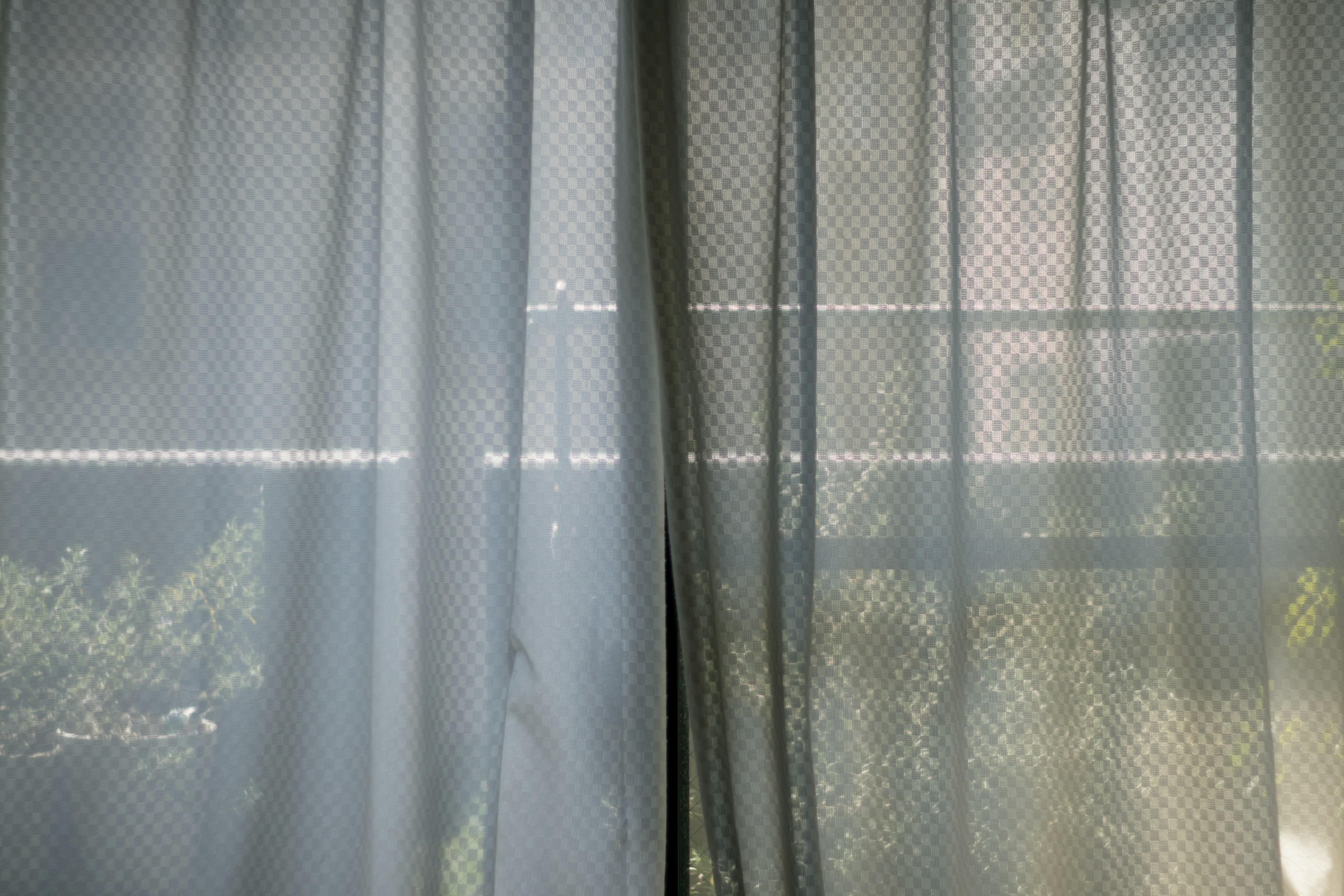 Sheer curtains revealing a glimpse of the outside scenery and light