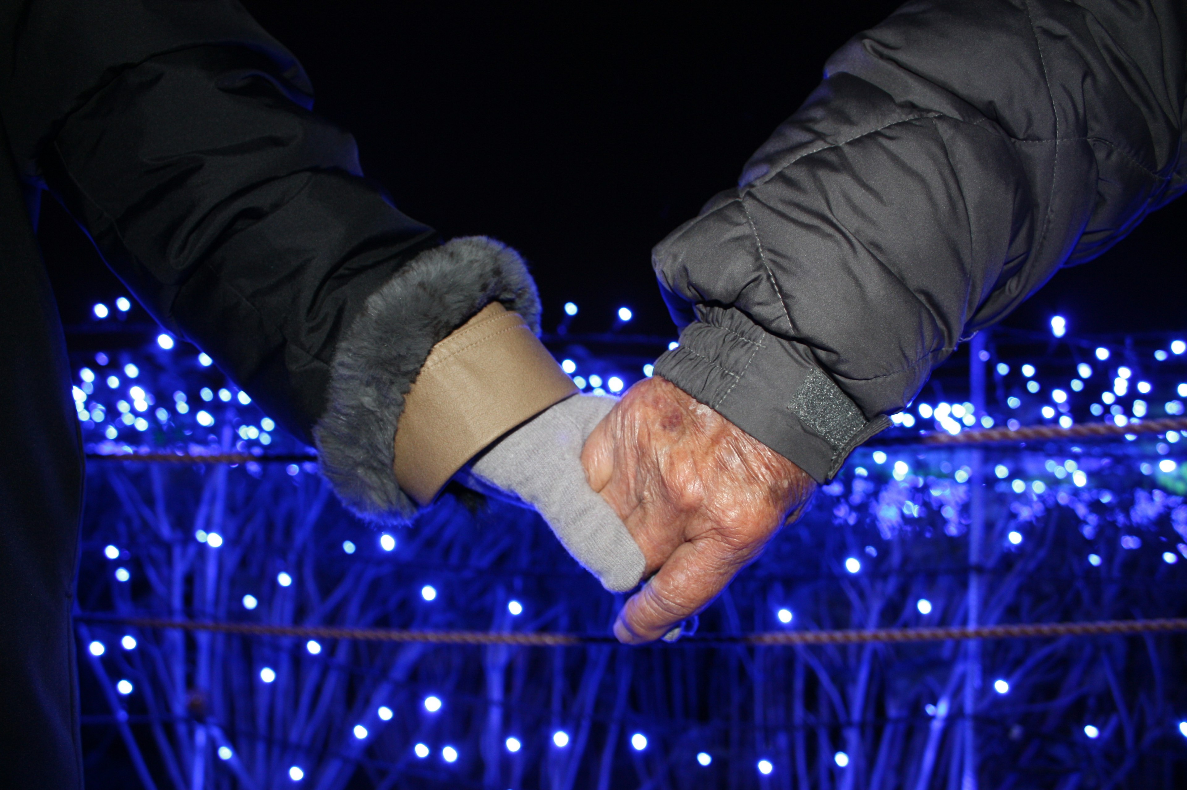 Dos manos entrelazadas en un entorno nocturno con luces azules de fondo