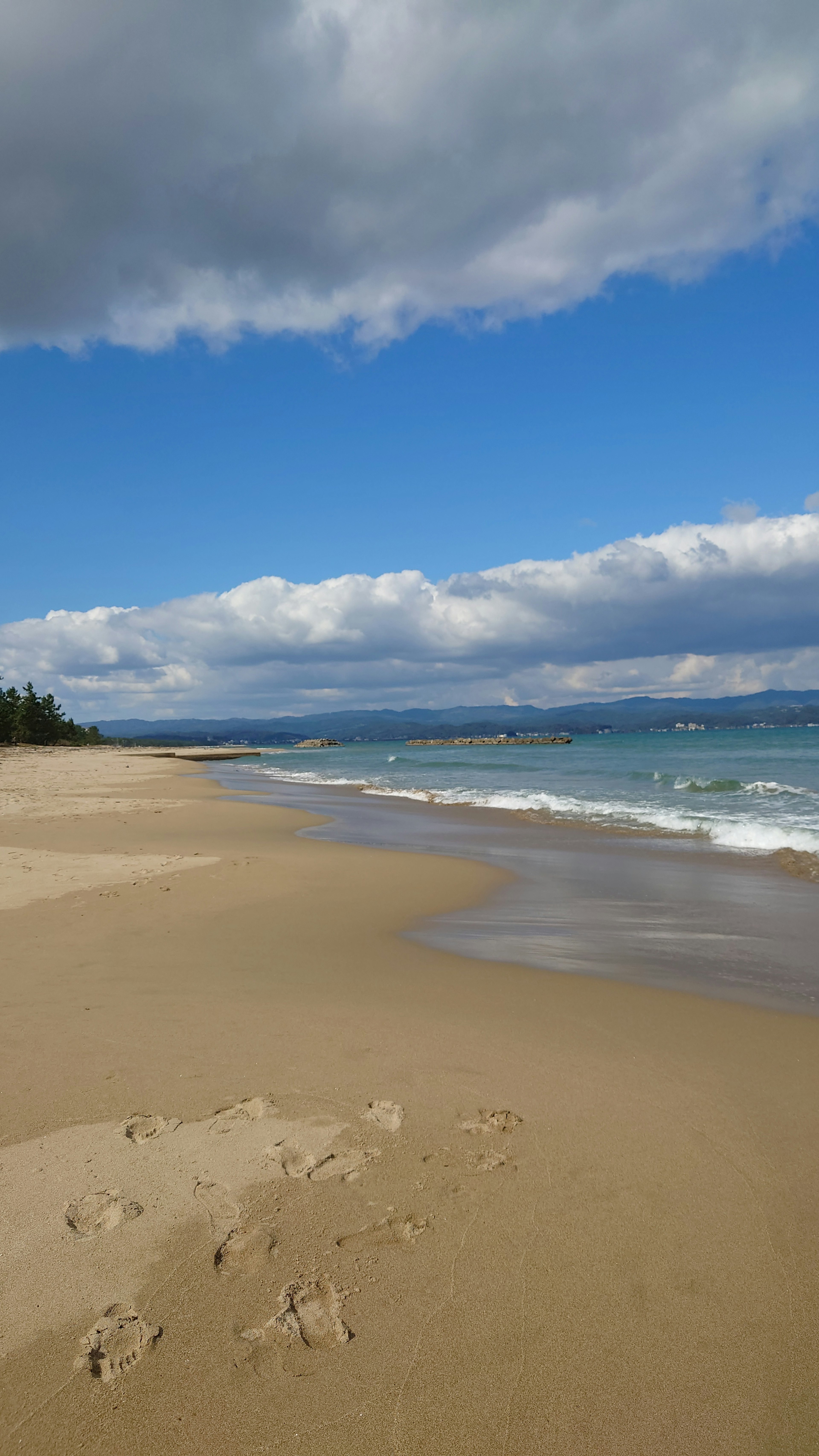 Pemandangan pantai dengan langit biru dan awan putih pantai berpasir dengan ombak lembut