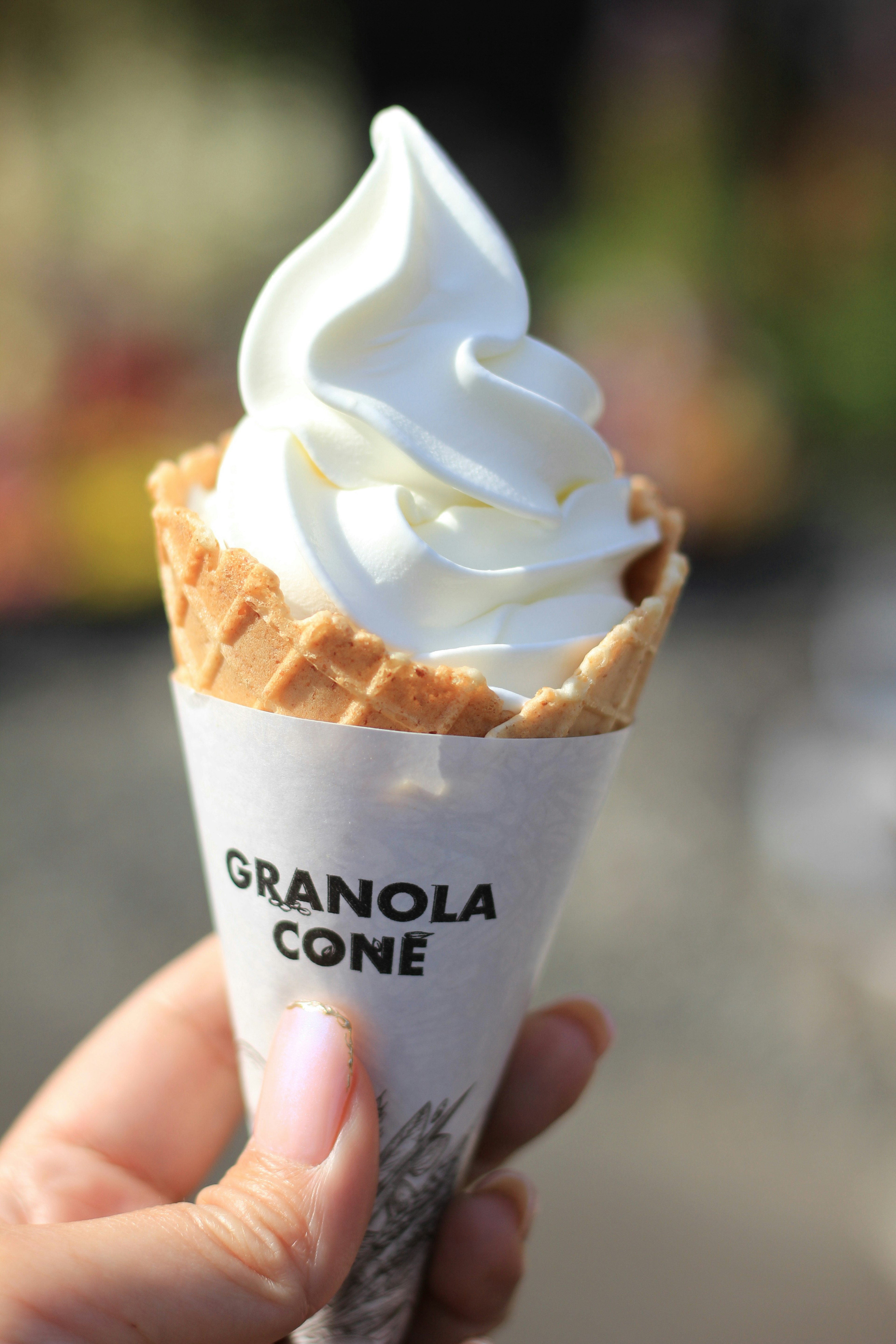 Helado suave en un cono de granola sostenido por una mano