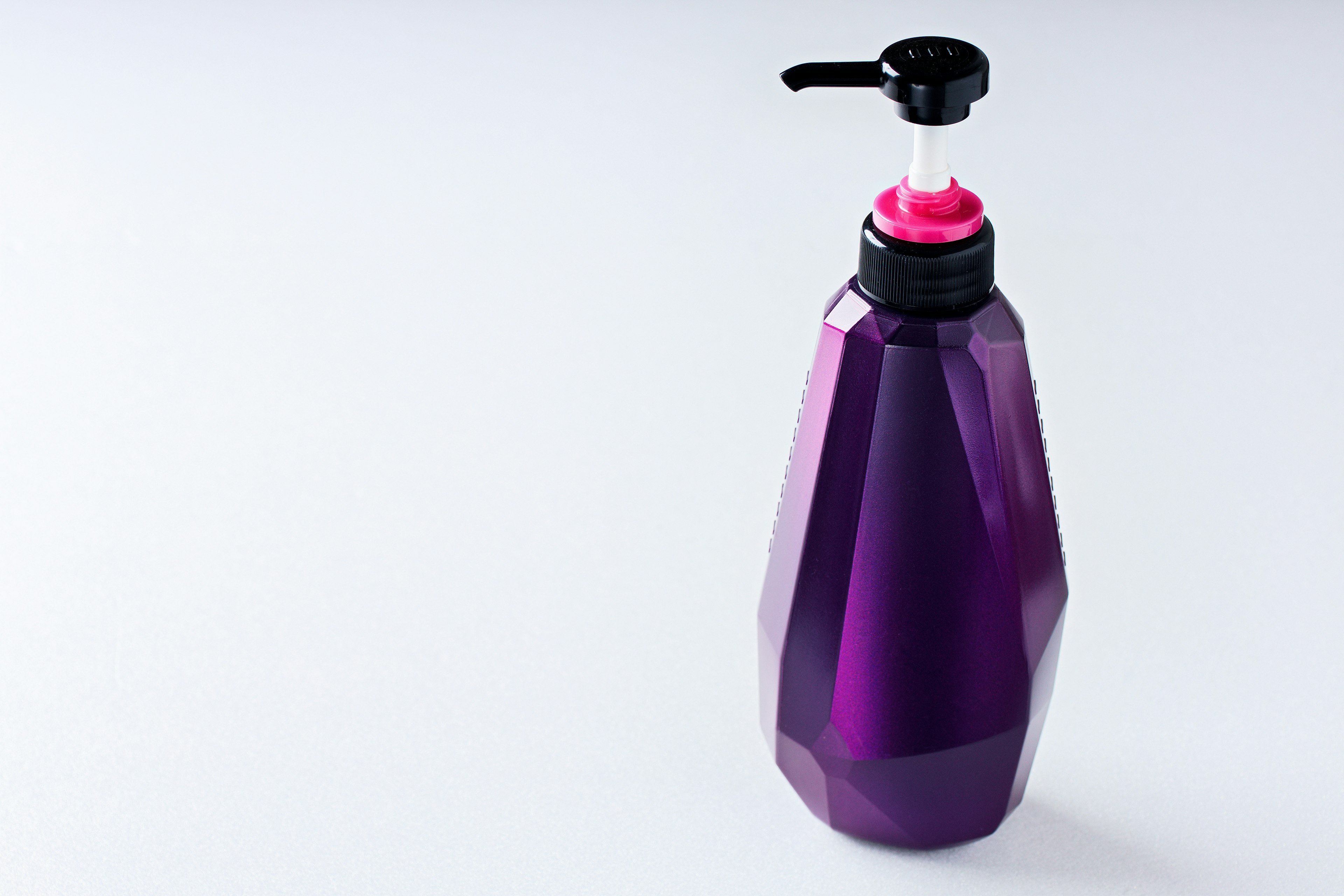 Purple geometric bottle with black pump and pink cap