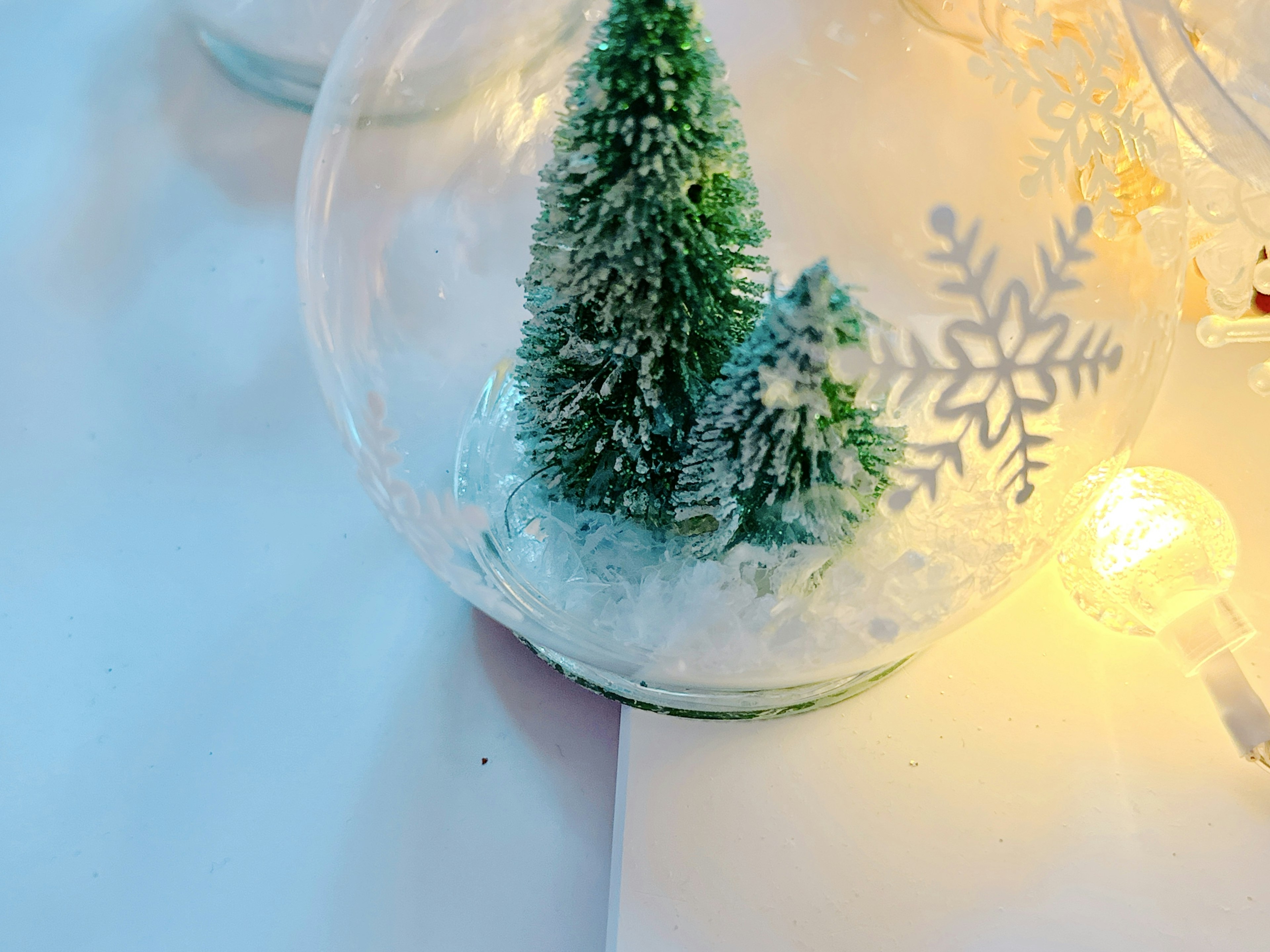 Adorno de vidrio con un árbol de Navidad verde y copos de nieve