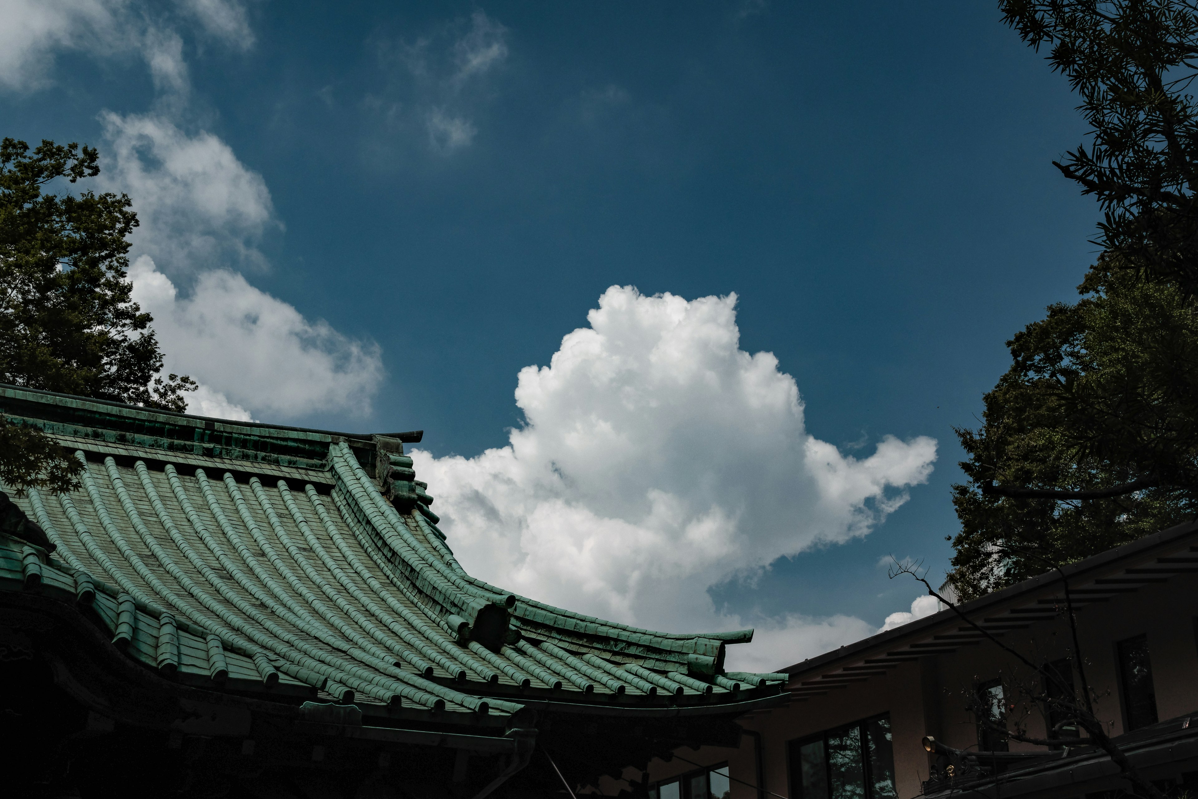 Traditional building with a green roof against a blue sky and white clouds