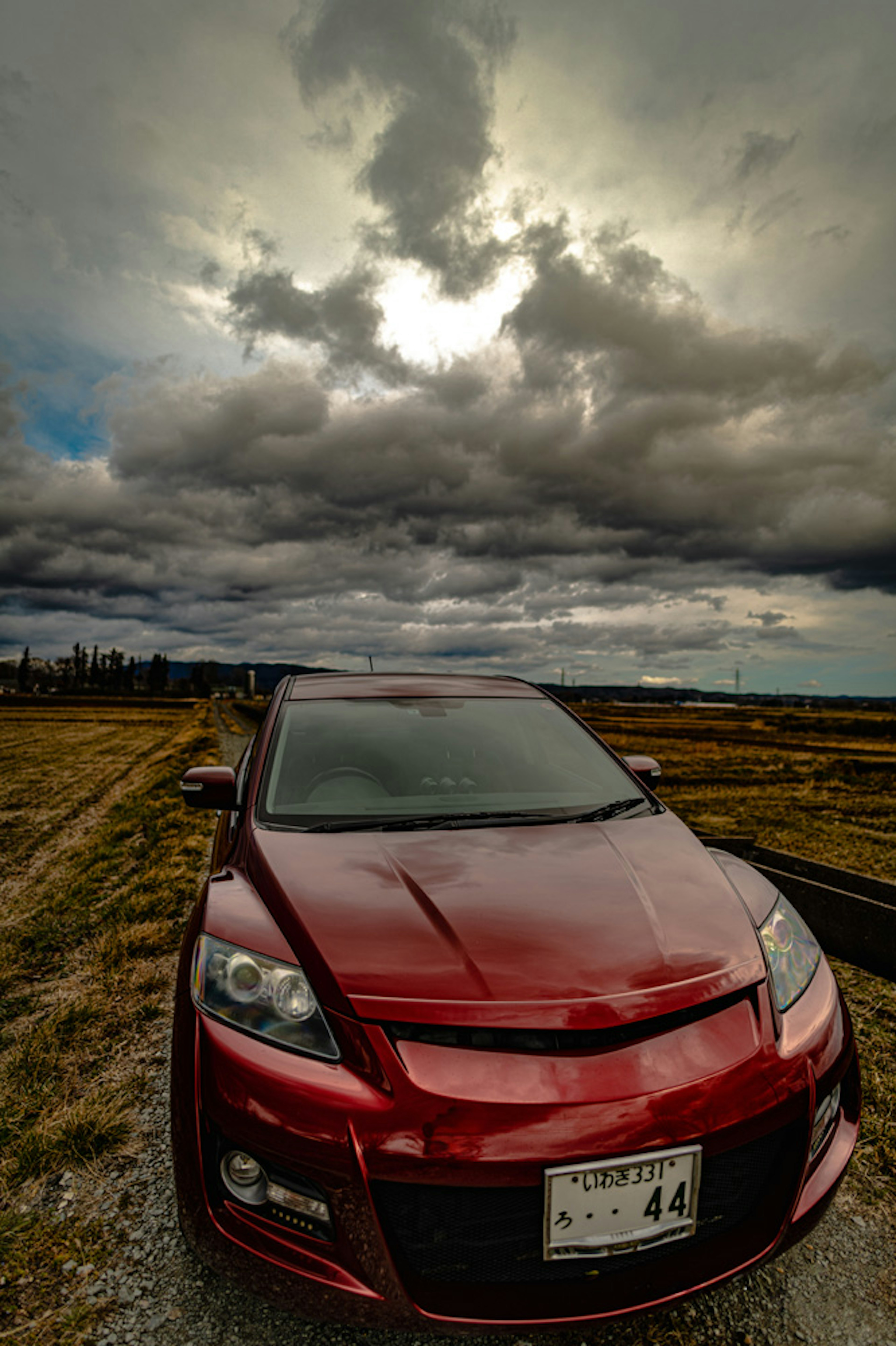 Red car with dramatic cloudy sky