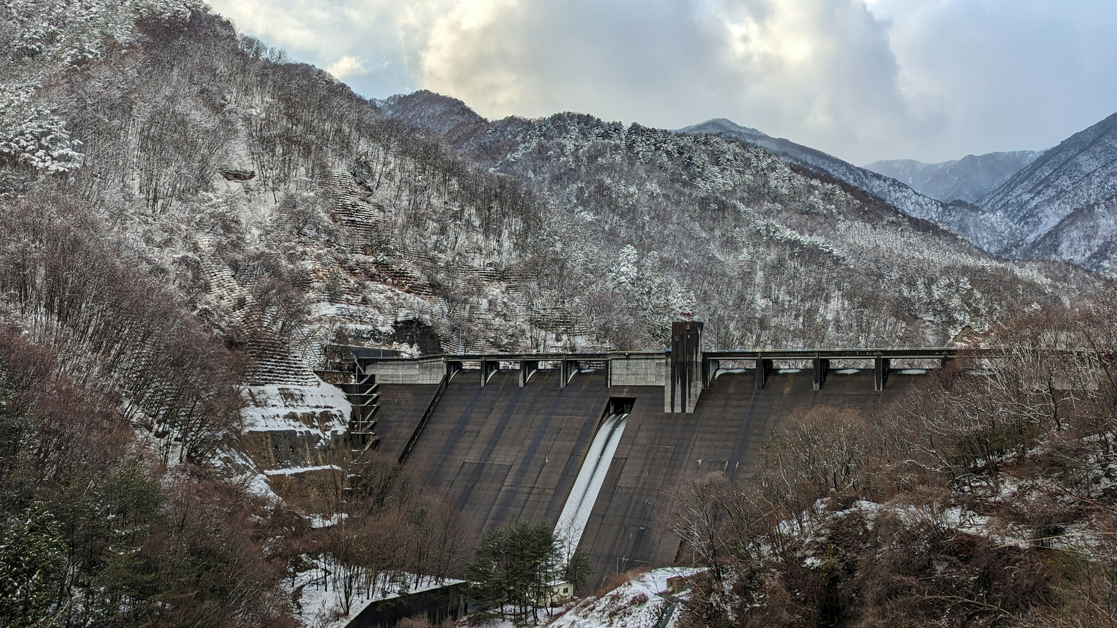 雪に覆われた山々の間に立つダムの風景