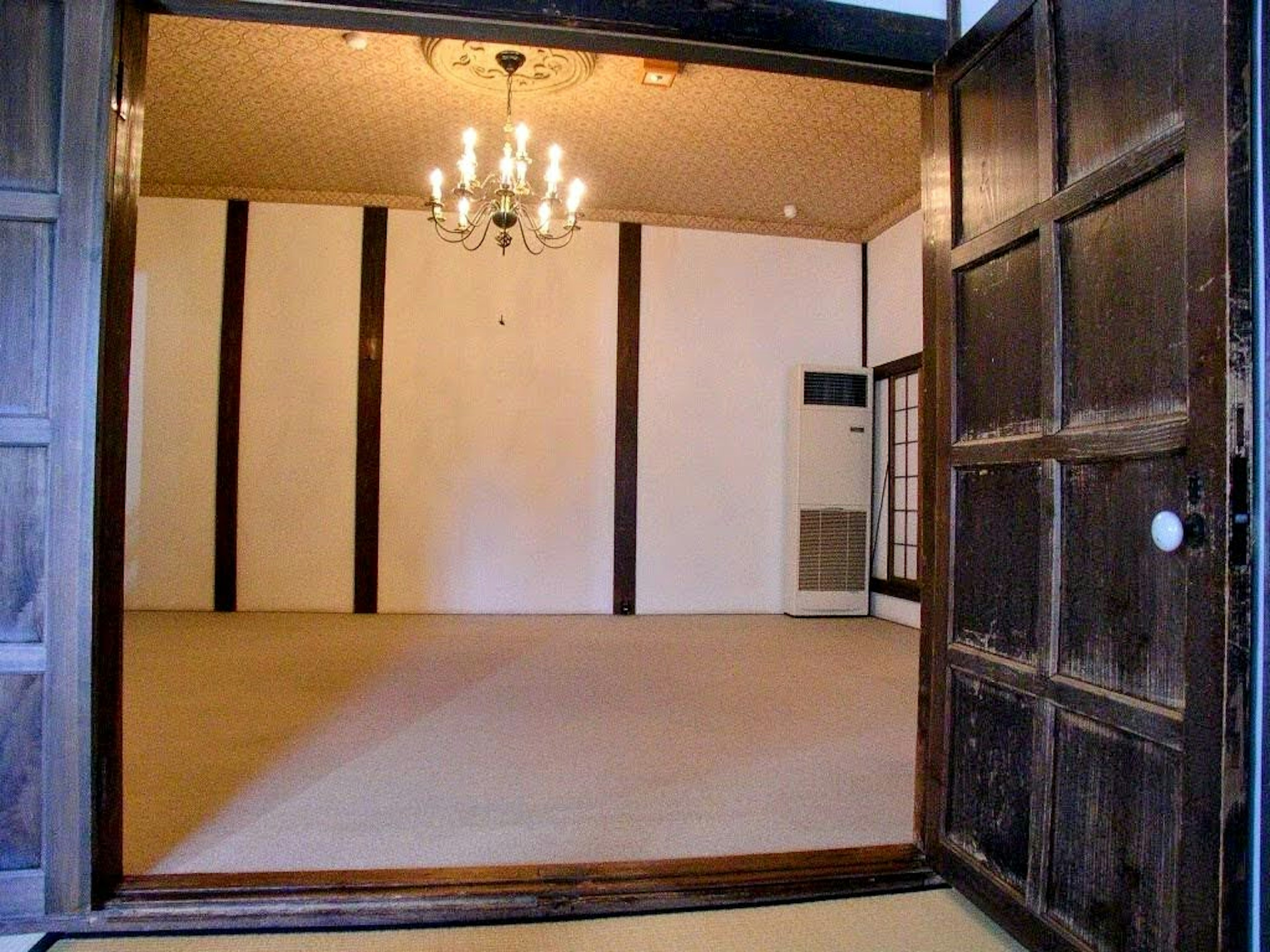 View of a spacious room from the entrance featuring a chandelier and wooden door