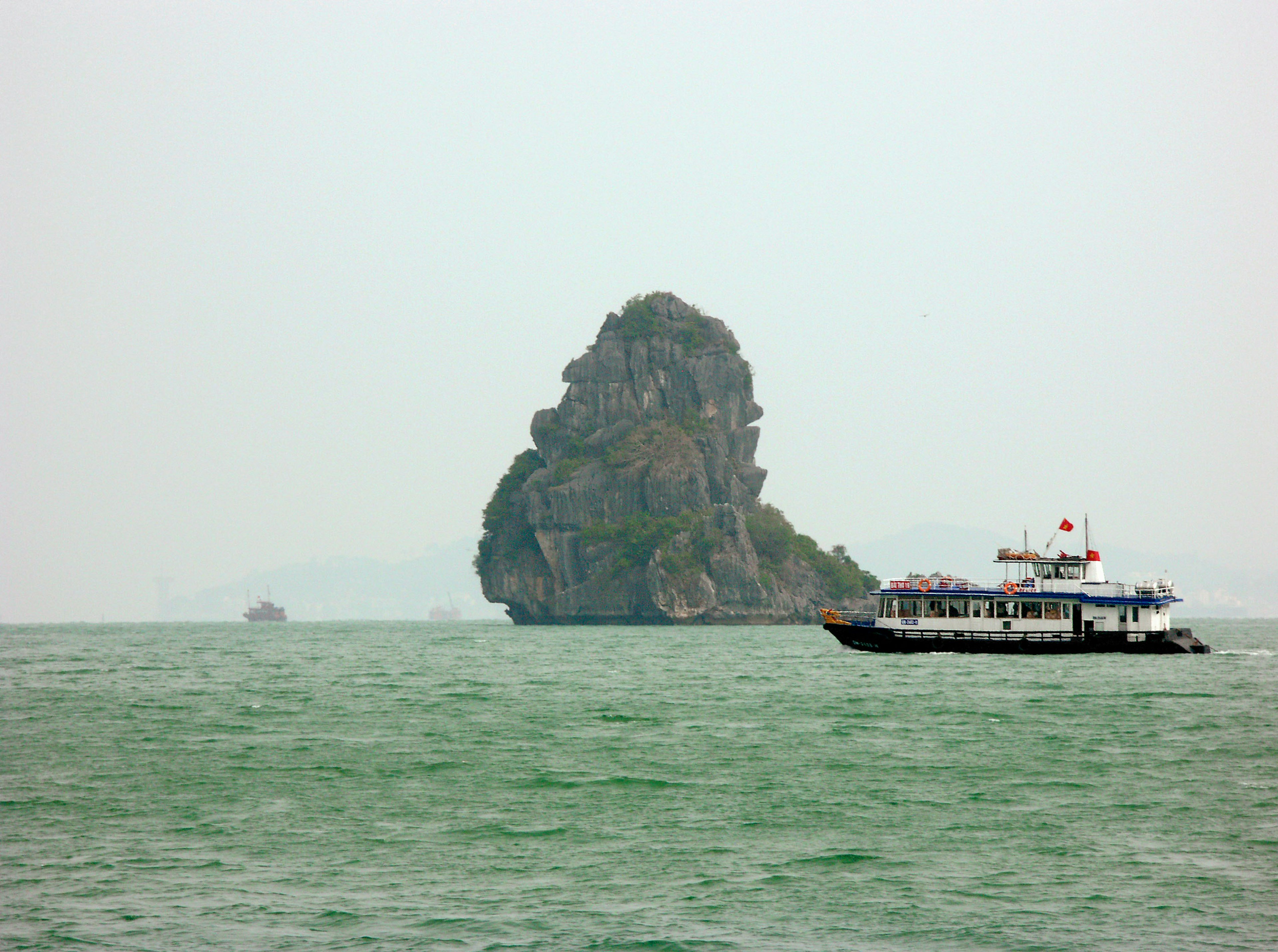 Pemandangan laut dengan pulau berbatu dan kapal dalam kondisi berkabut