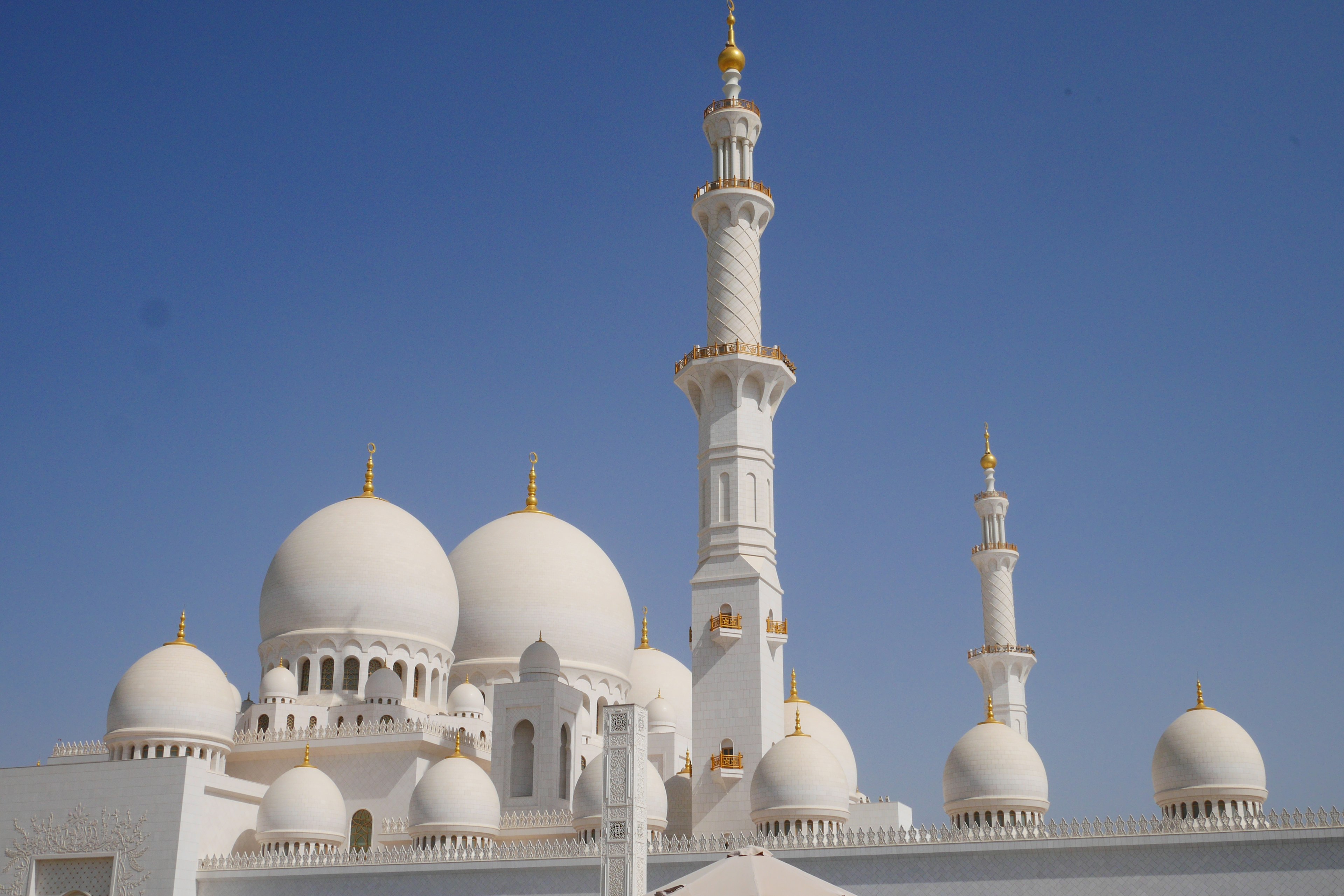 Exterior view of a mosque featuring white domes and minarets