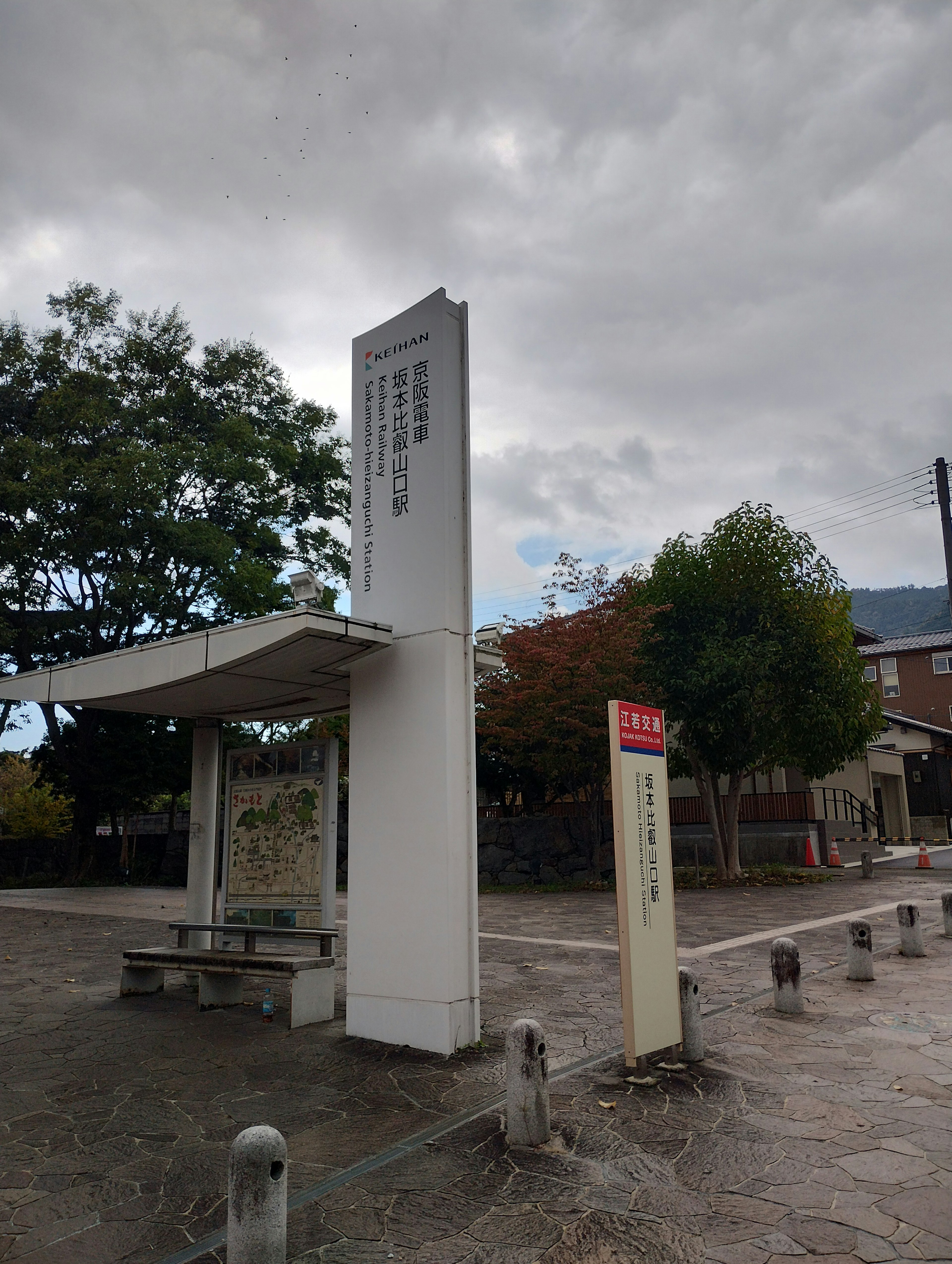 Papan pemberhentian bus dengan pohon di sekitar dan langit mendung