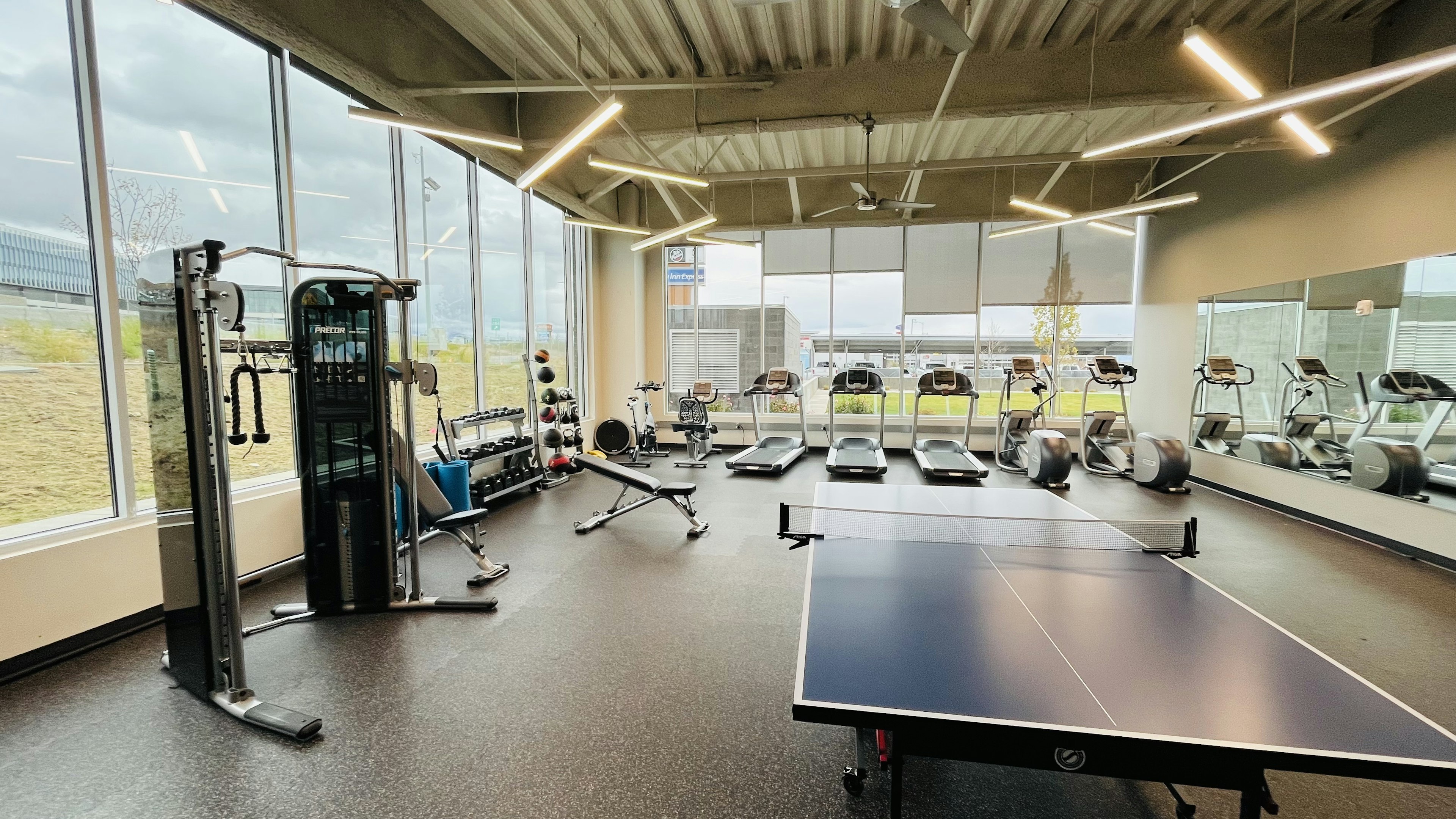 Sala de fitness iluminada con equipo de ejercicio y mesa de ping pong