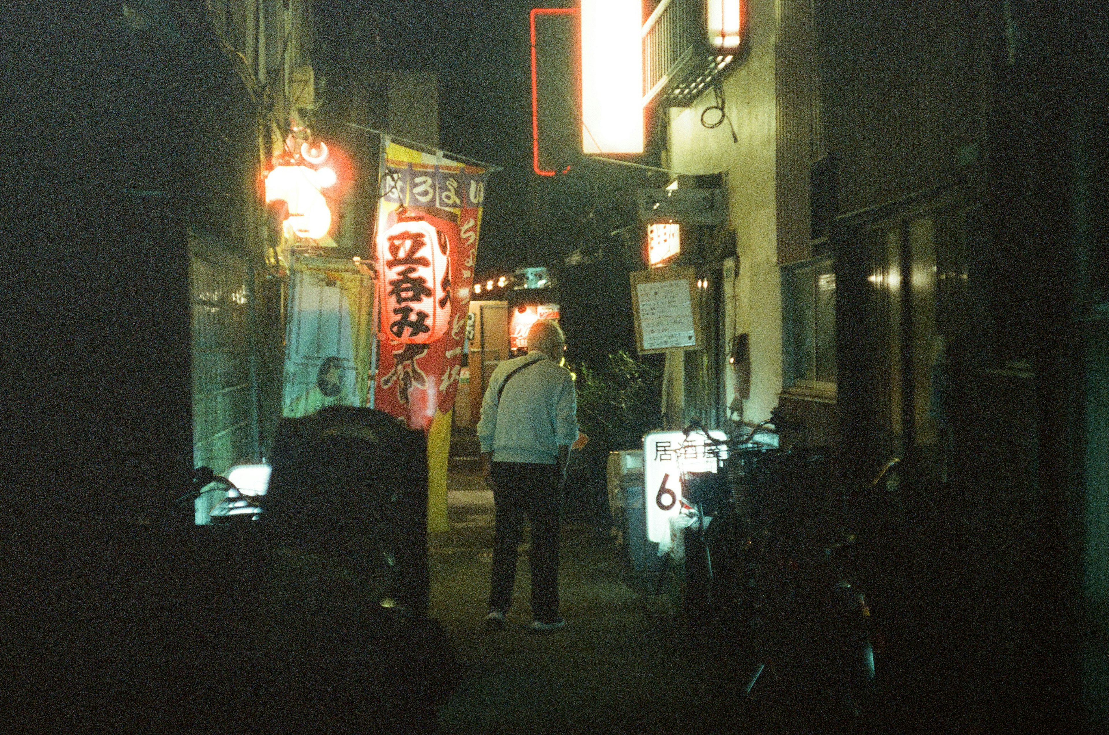 Person standing in a narrow alley with bright signs