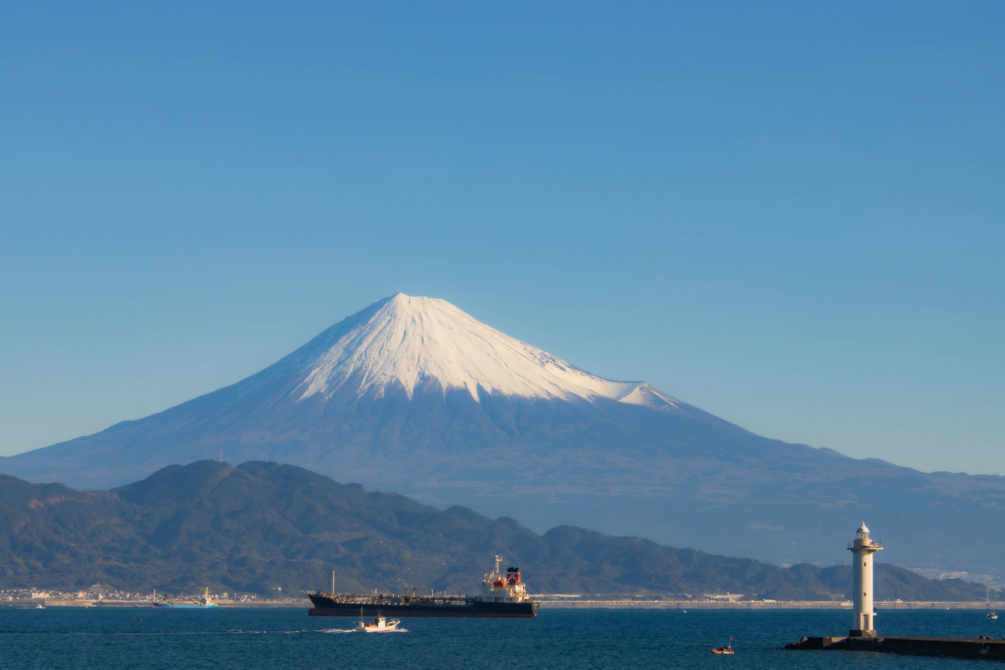 Vista del monte Fuji con un faro y barcos en el mar