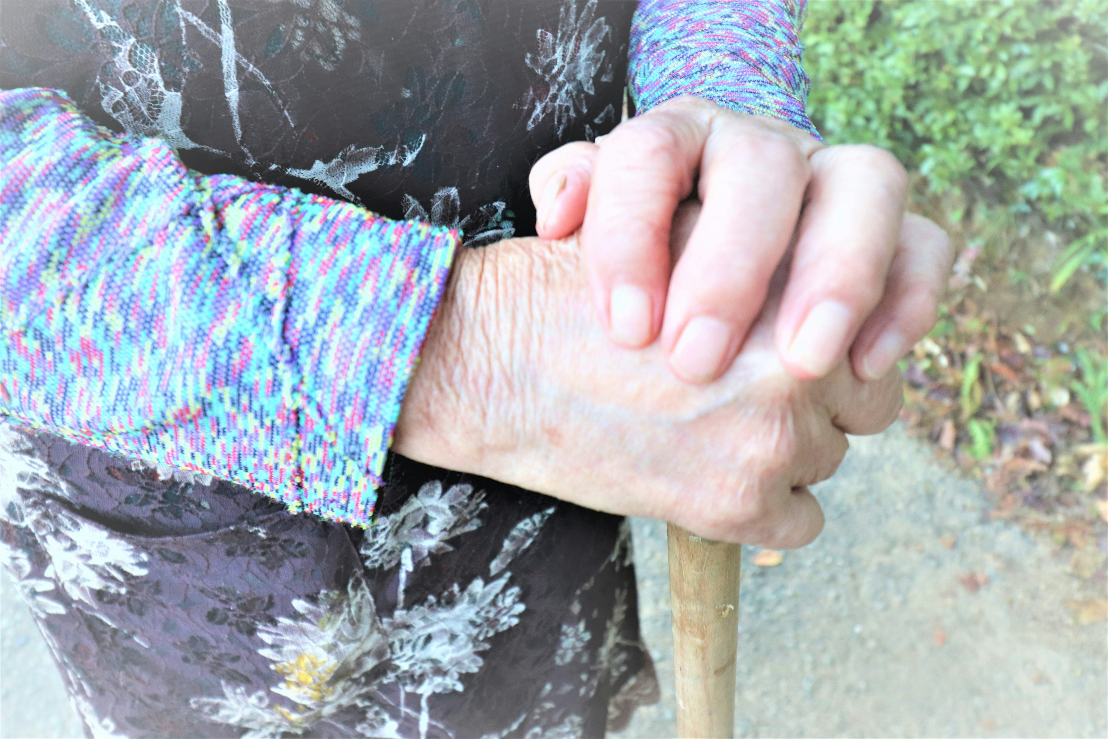 Close-up of an elderly person's hands holding a cane