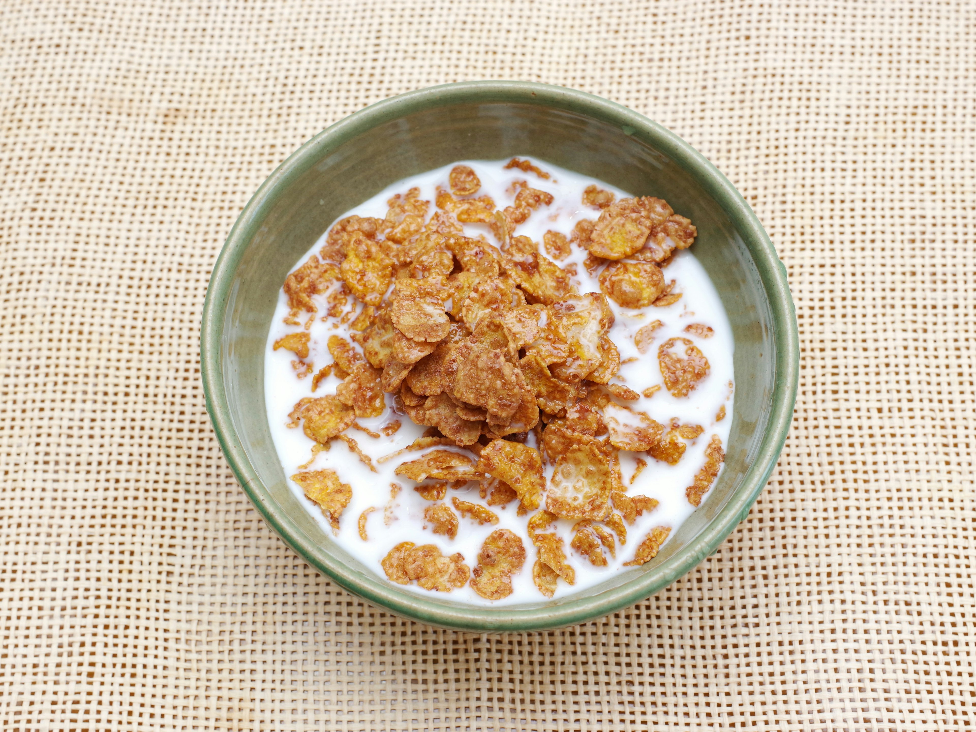 Schüssel mit Cornflakes und Milch auf einem strukturierten Hintergrund