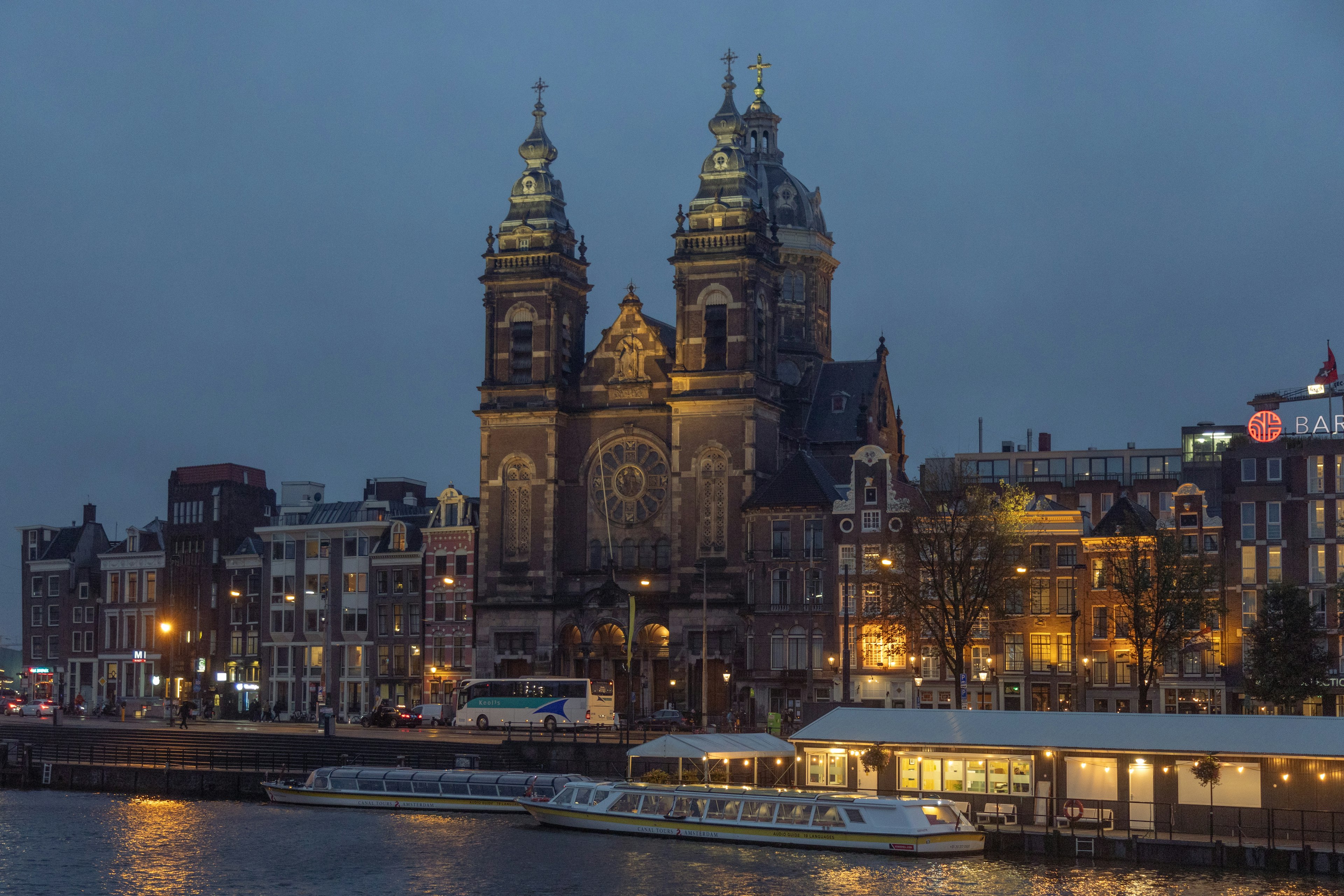 Grand church facade illuminated at night in Amsterdam with surrounding buildings