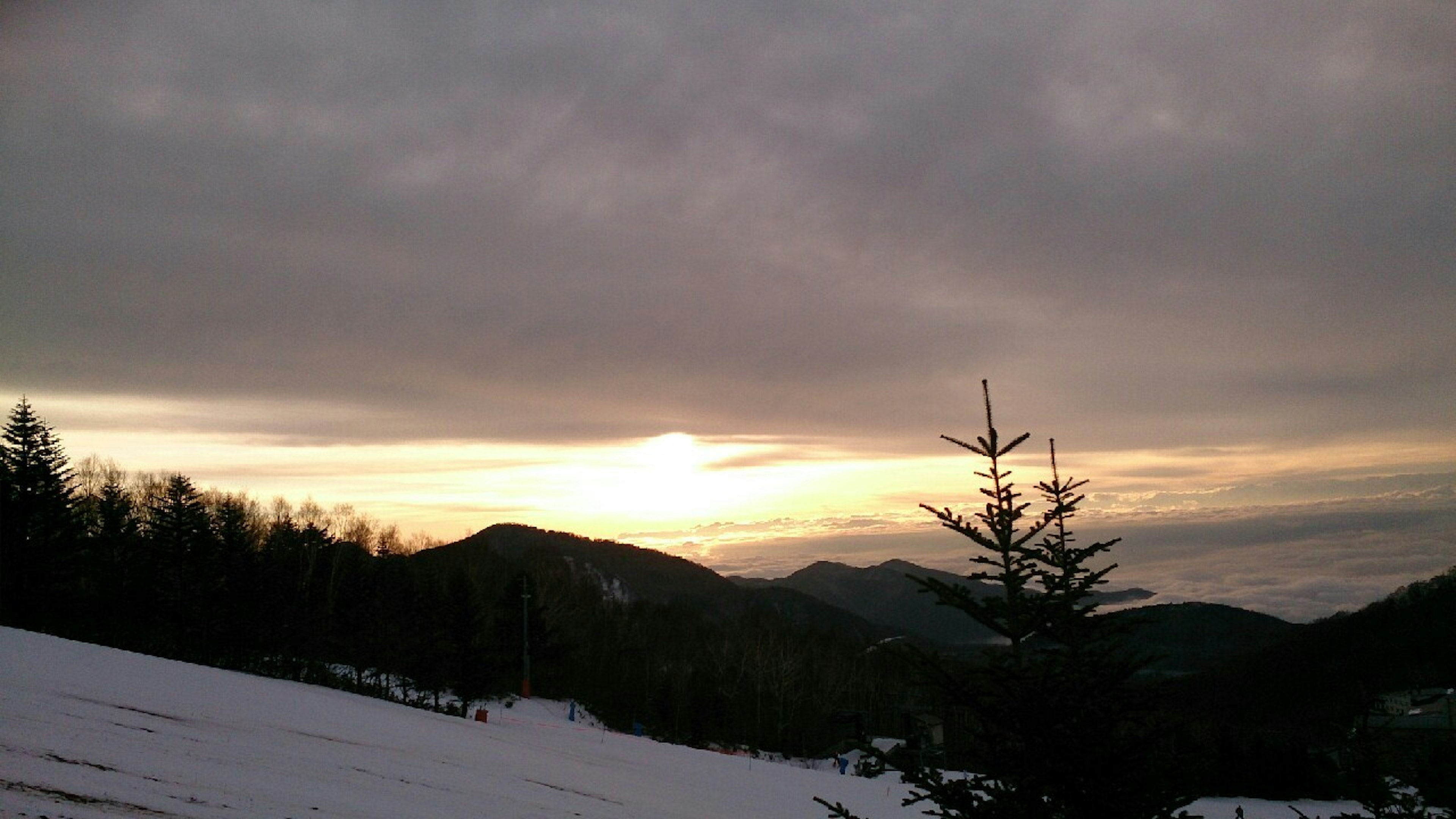 Montagnes enneigées sous un ciel nuageux au coucher du soleil