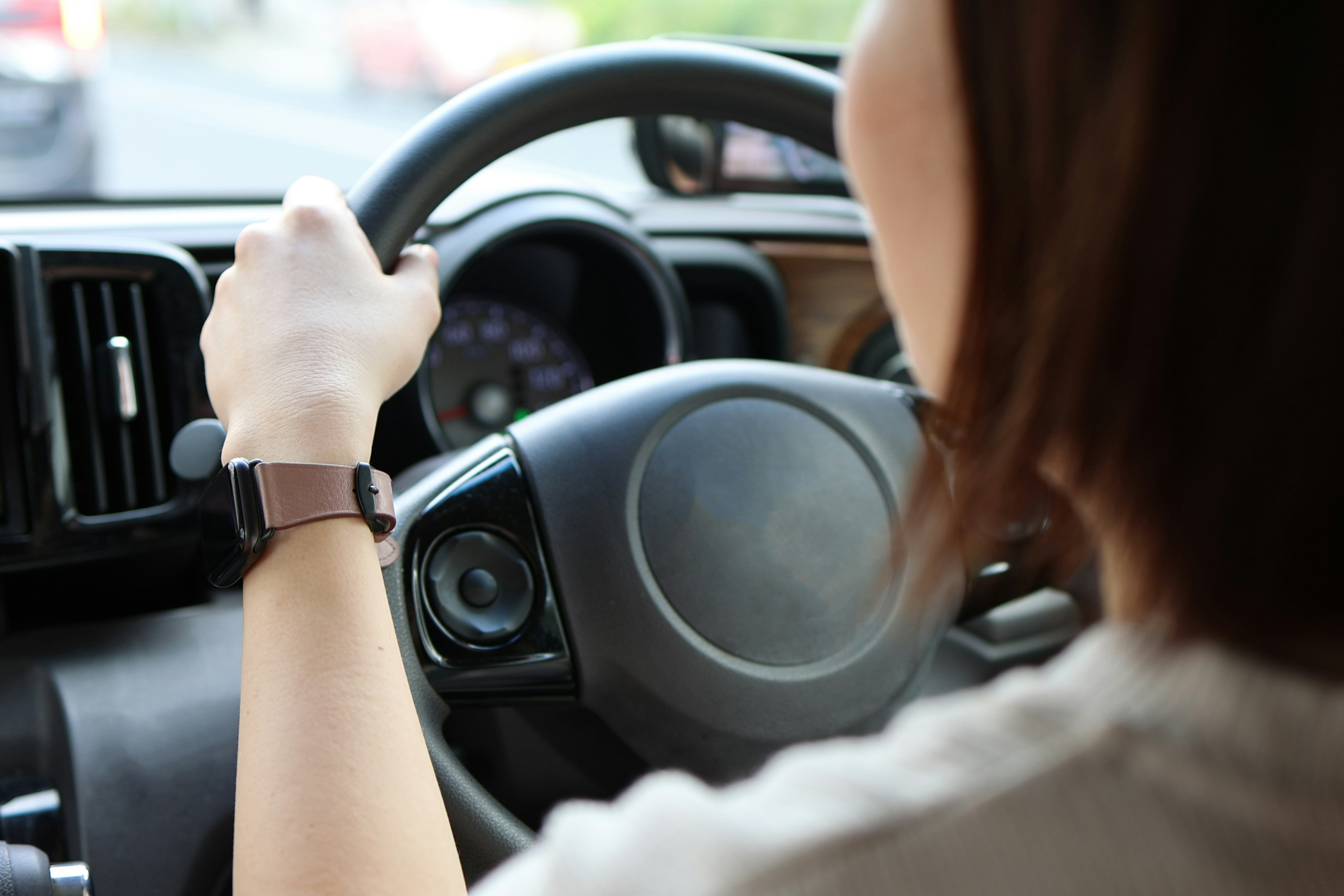 A woman's hand gripping the steering wheel while driving