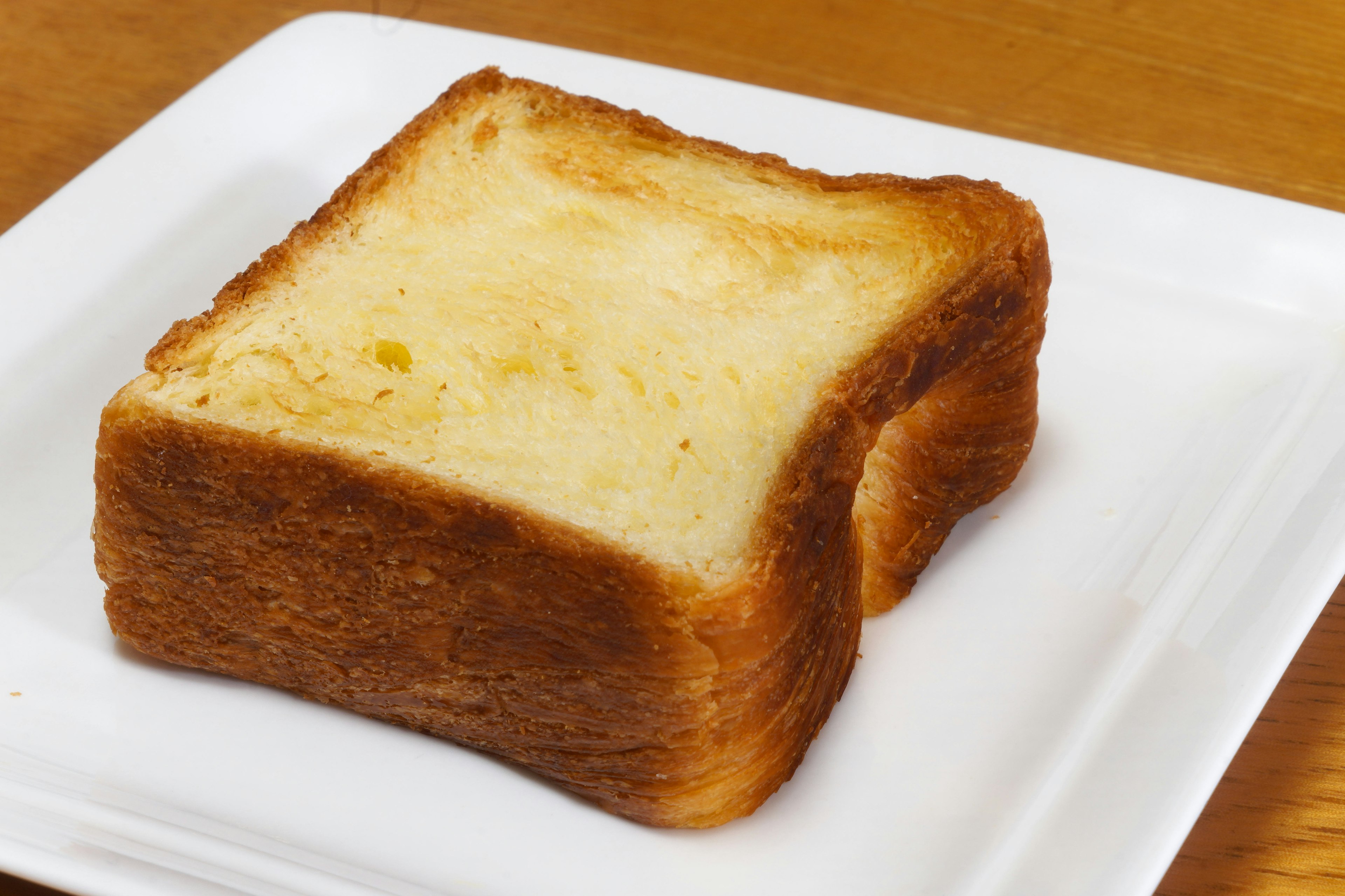 A slice of toast on a white plate with a golden crispy texture