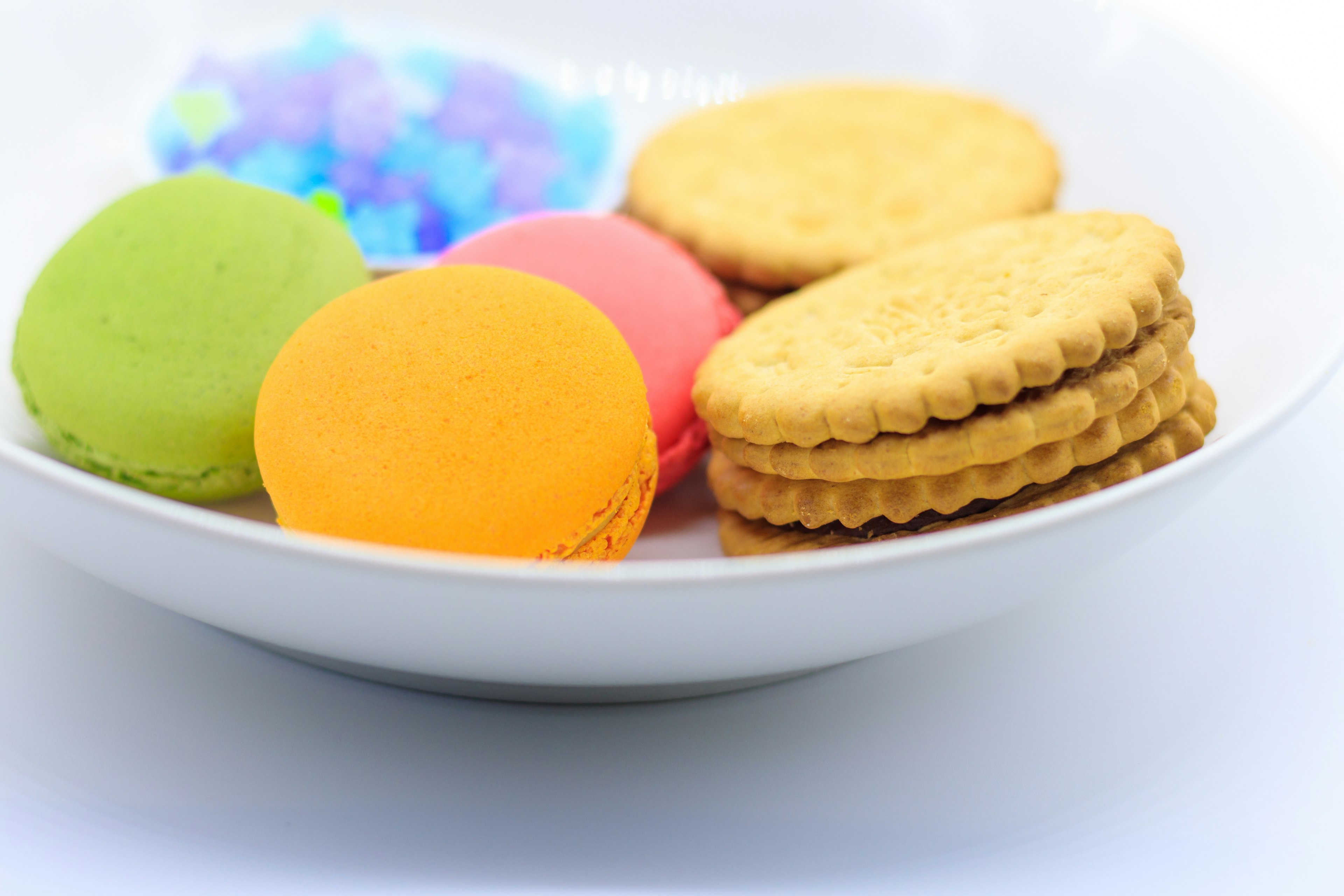 Macaron berwarna-warni dan biskuit disusun di atas piring putih