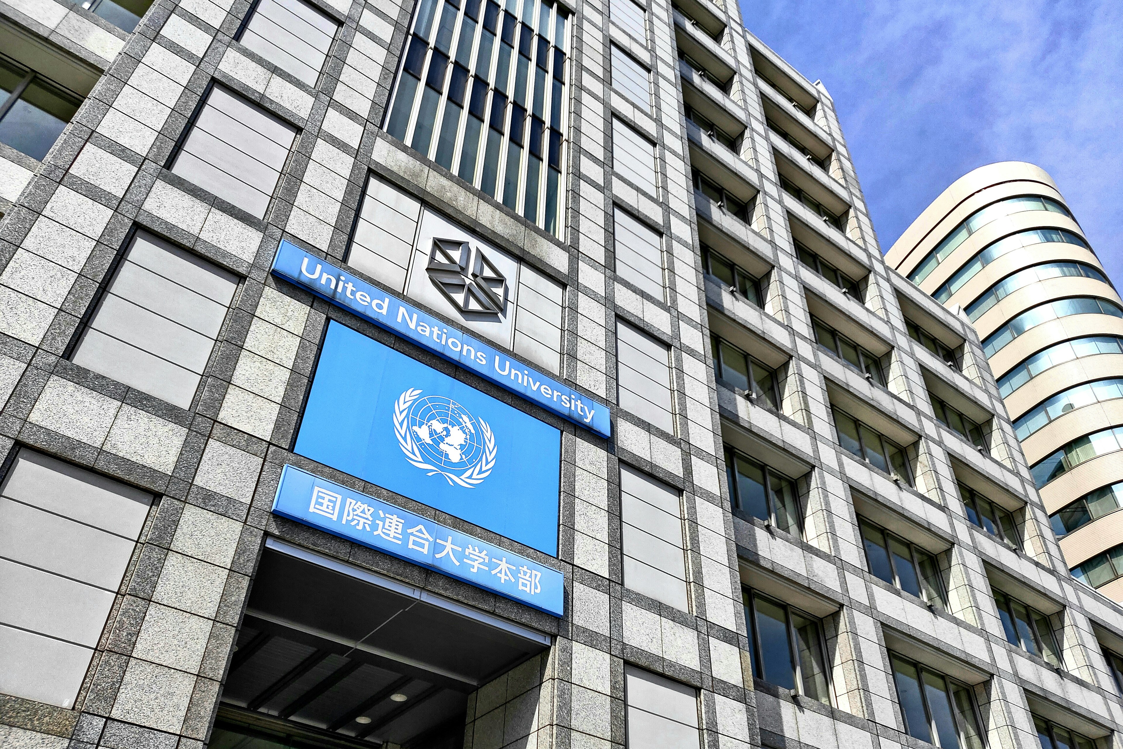 Vue extérieure du bâtiment de l'Université des Nations Unies avec un panneau bleu proéminent