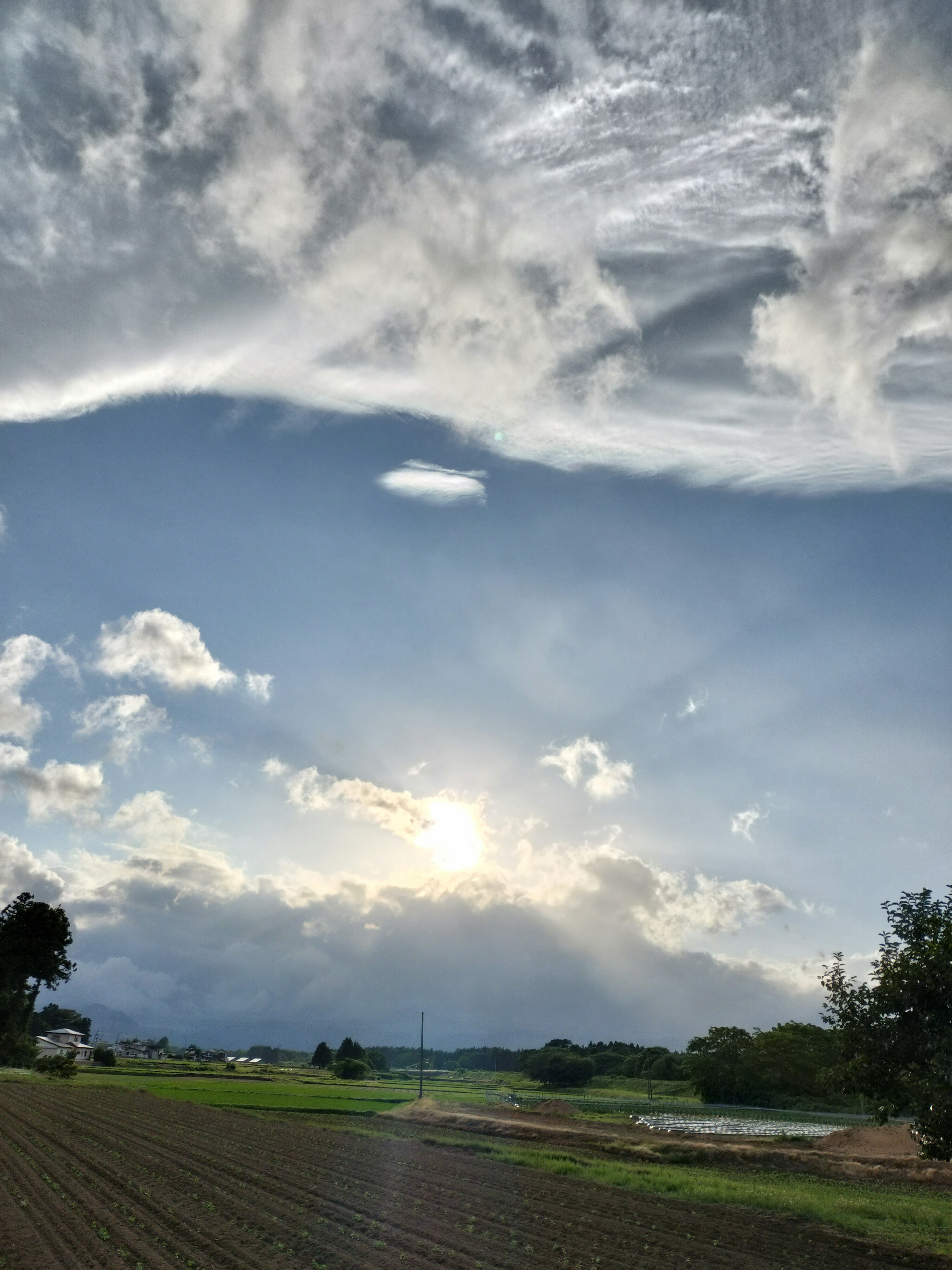 青空に広がる雲と太陽の光が差し込む風景