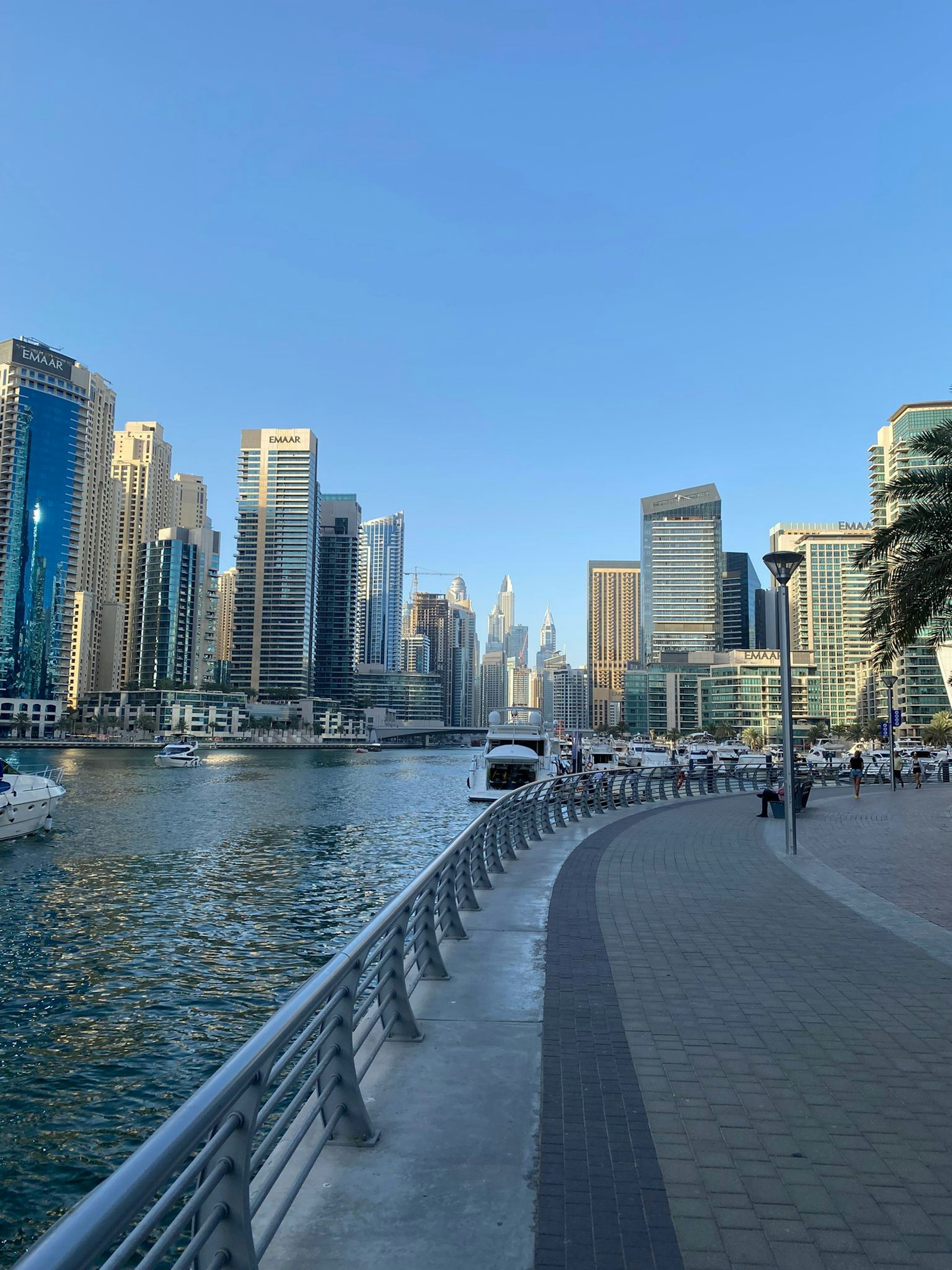 Moderne Wolkenkratzer entlang einer Uferpromenade bei klarem blauen Himmel