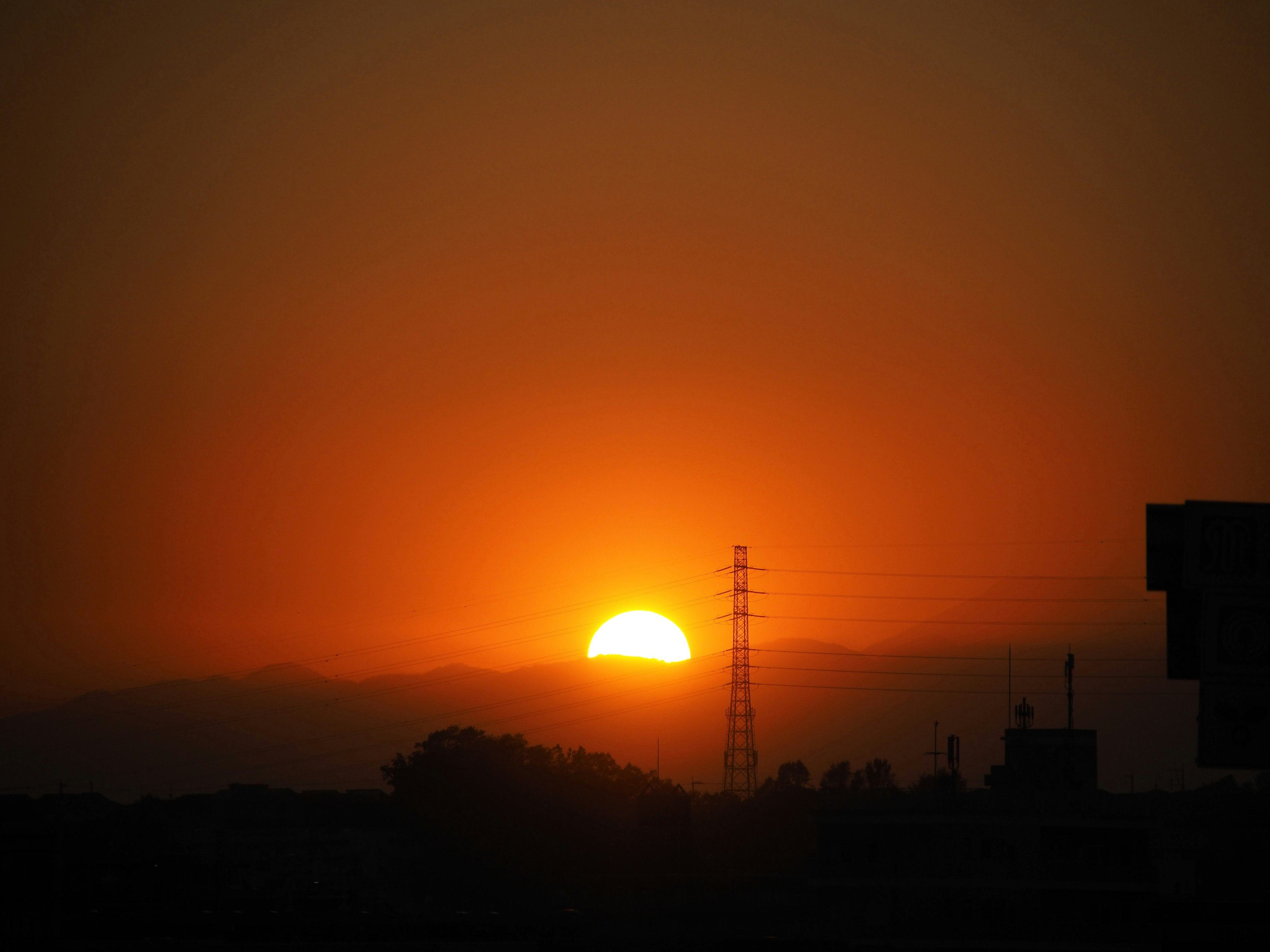 Silhouette der untergehenden Sonne mit einem Strommast